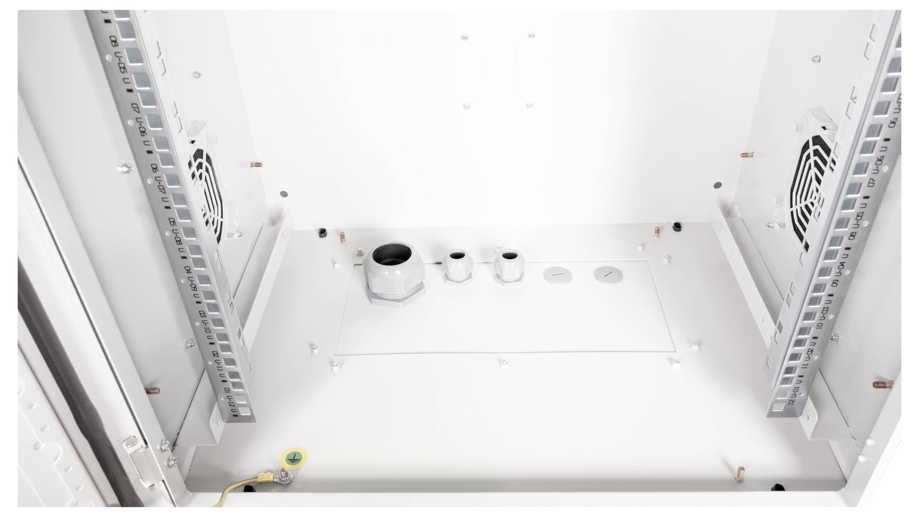 Blick in einen leeren Schrank mit Lüftern und Kabelöffnungen, bereit zur Installation von elektronischen Geräten.