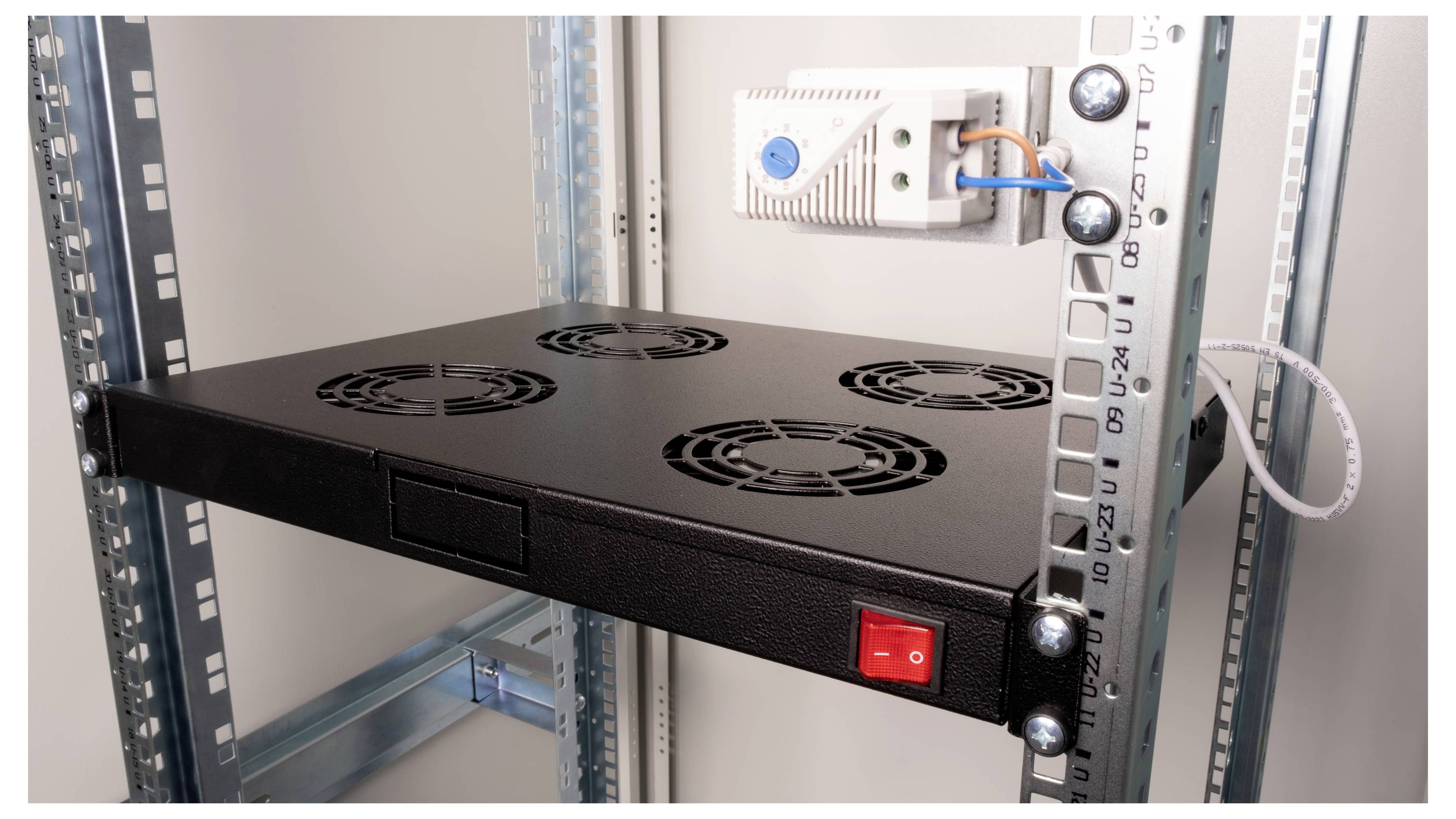 Ein offenes Metallregal mit eingebautem Lüftersystem und rotem Schalter in einem Serverschrank. Eine weiße Steckdose ist montiert.