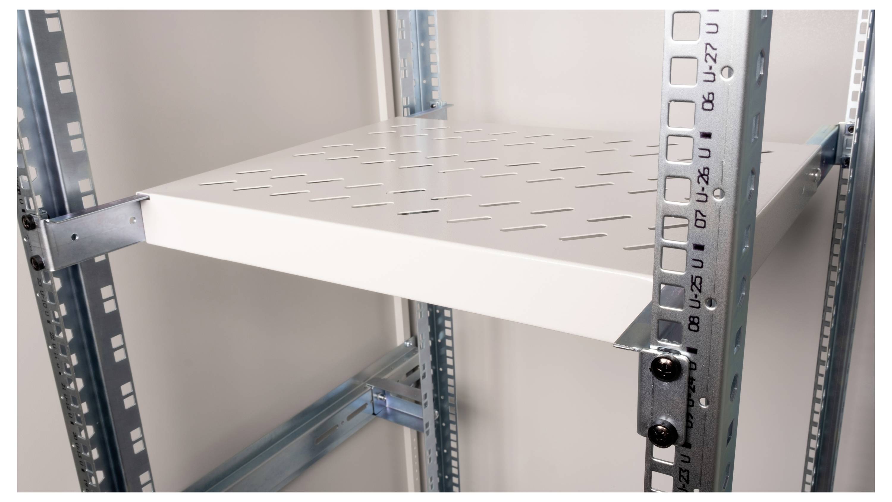 Ein metallisches Regal mit verstellbaren Höhen, gezeigt von innen. Es hat eine perforierte weiße Regalfläche und robuste, graue Streben.