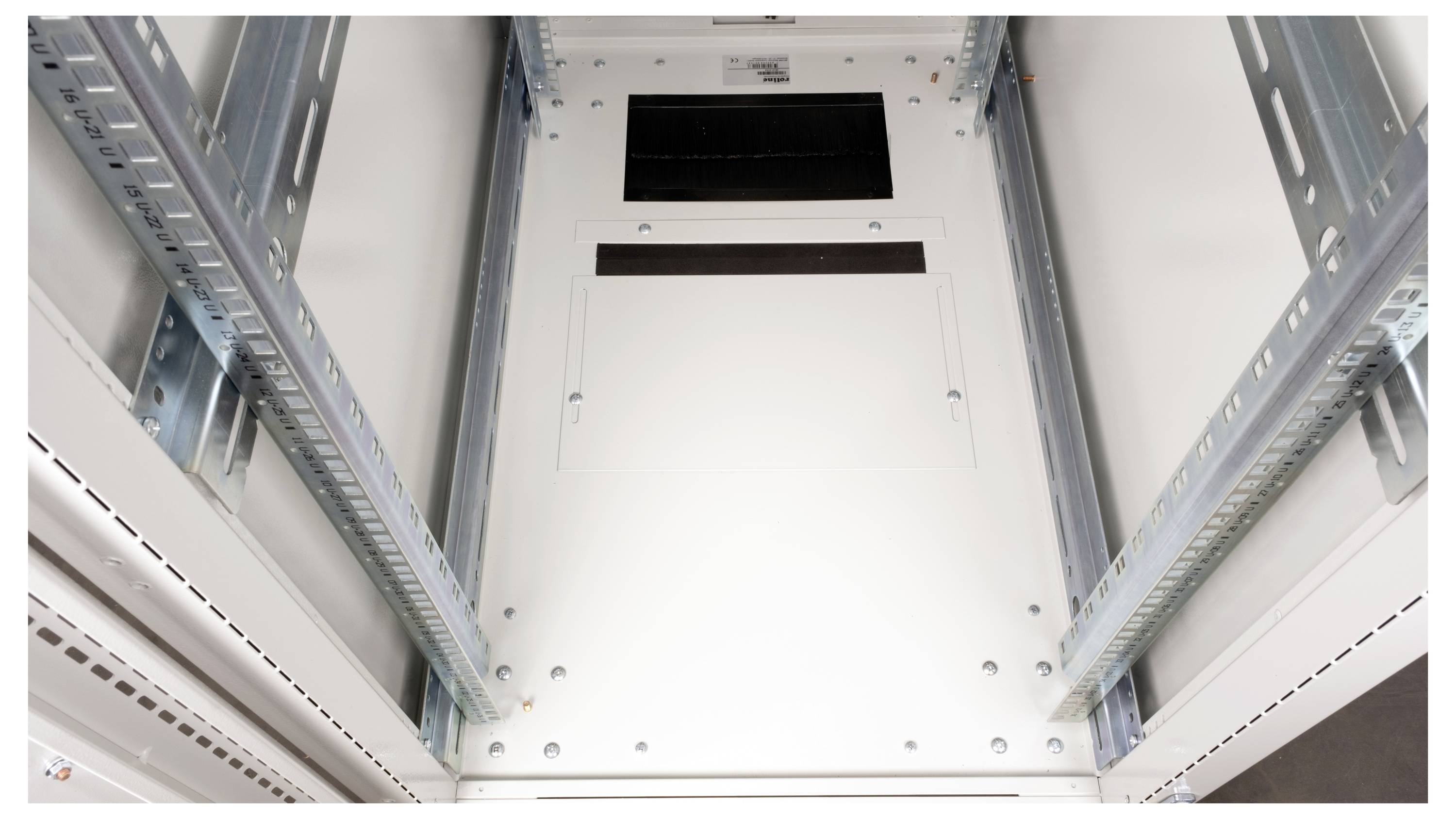 Innenansicht eines Metallschranks mit Schienen, wahrscheinlich für Server oder elektronische Geräte vorgesehen, mit einer weißen Tür im Hintergrund.