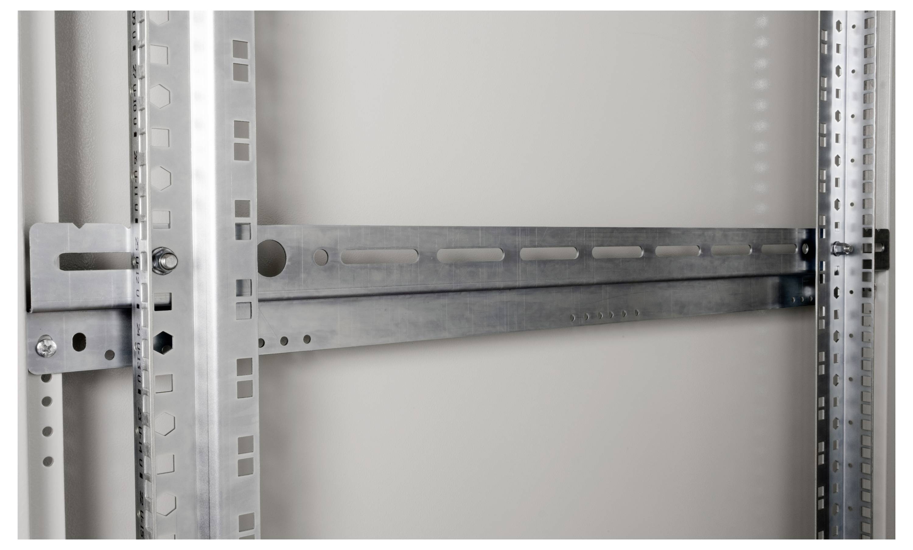 Stahlrahmen mit perforierten vertikalen und horizontalen Metallstäben, verwendet für strukturelle Unterstützung oder Montage, vor neutralem Hintergrund.
