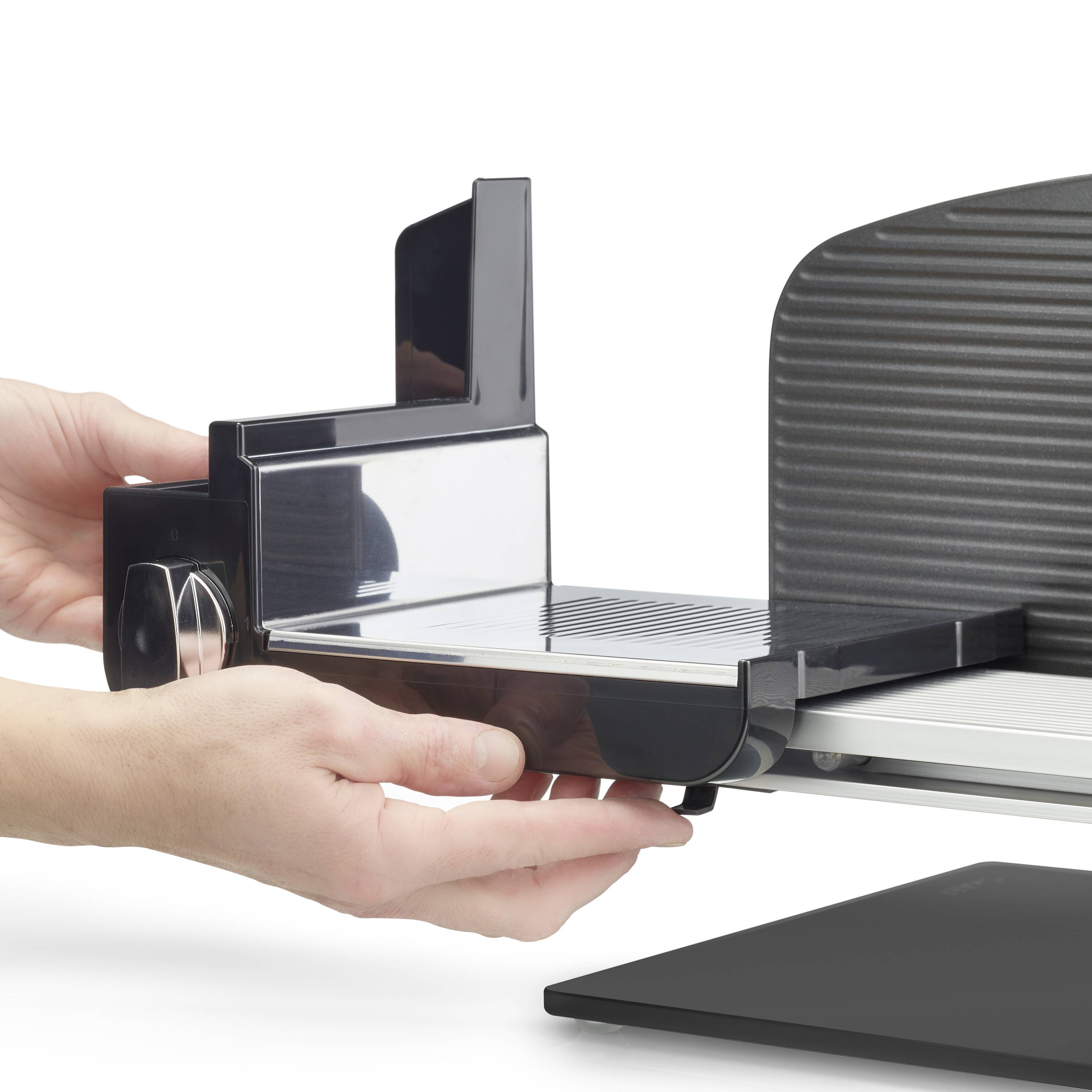 Eine Person justiert einen modernen Allesschneider. Die Schneidefläche und die Einstellungen sind sichtbar.