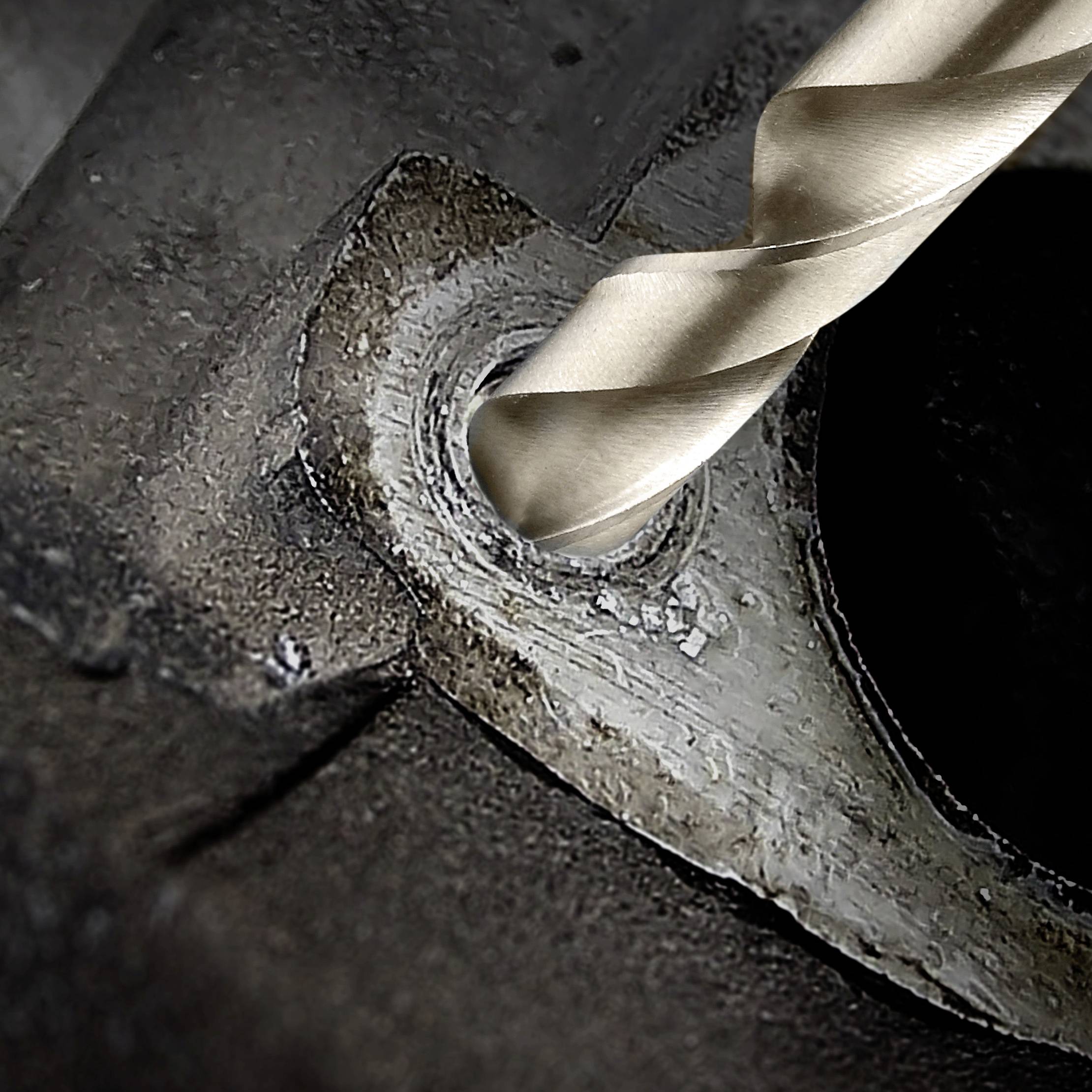 Nahaufnahme eines Bohrers, der ein rundes Loch in ein Metallstück bohrt. Es zeigt den Vorgang des Metallbohrens aus nächster Nähe.