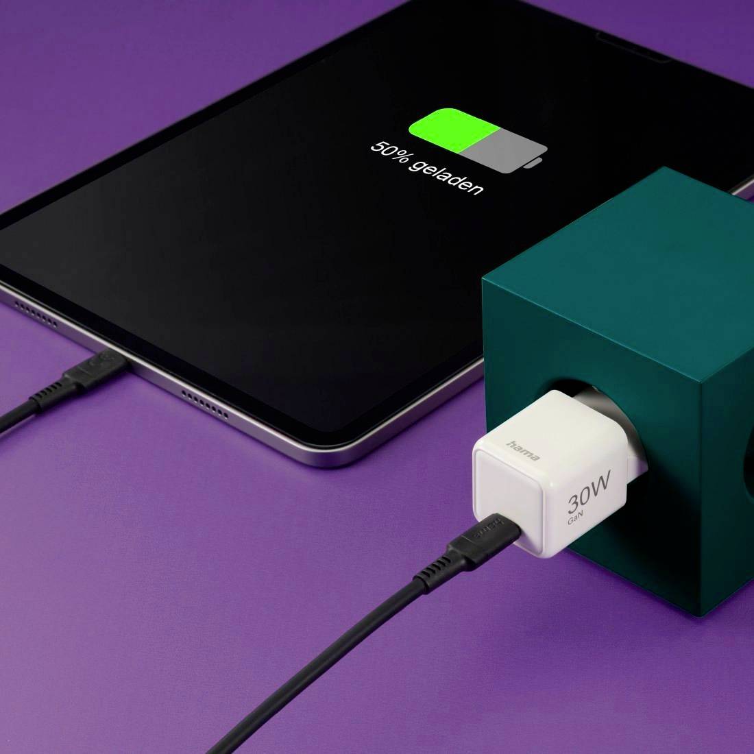 Ein Smartphone wird auf einem lila Tisch drahtlos aufgeladen, der Bildschirm zeigt '50% geladen'.