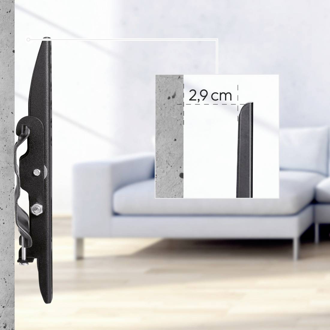 Ein flacher TV-Halter an der Wand, ragt 2,9 cm hervor. Im Hintergrund ein Sofa im hellen Wohnzimmer.