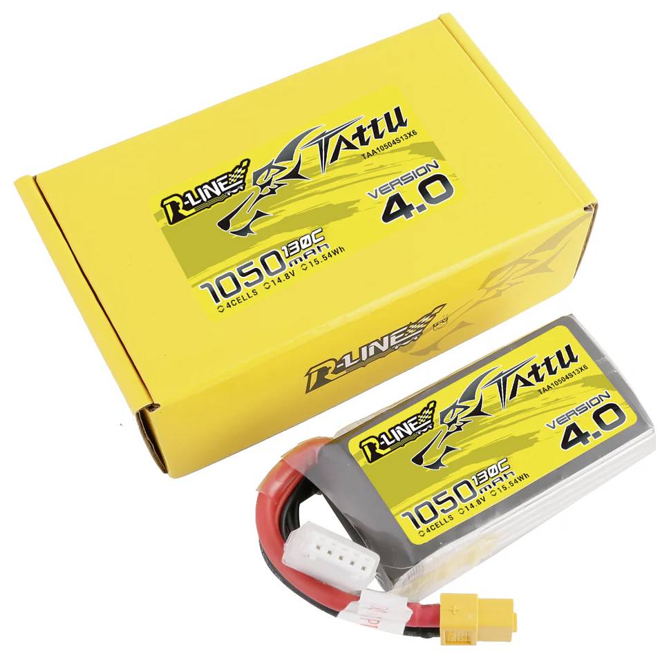 Ein gelber Karton und ein Akkupack mit der Aufschrift 'Tattu R-Line 4.0, 1050mAh, 4S1P, 14.8V, 155.4Wh, 130C'.