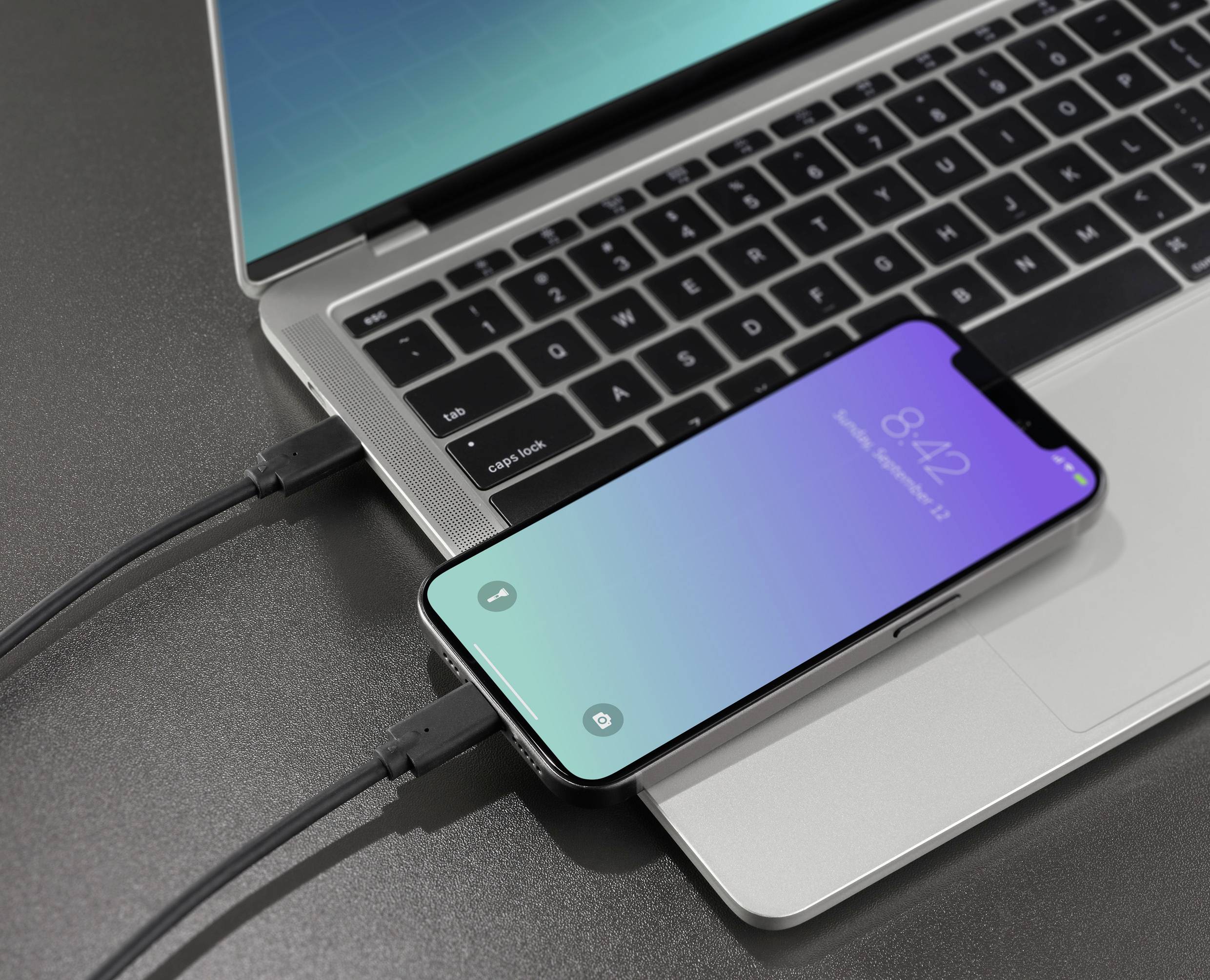 Ein Smartphone ist per USB-Kabel mit einem Laptop verbunden, beide Geräte zeigen Ladeaktivität.