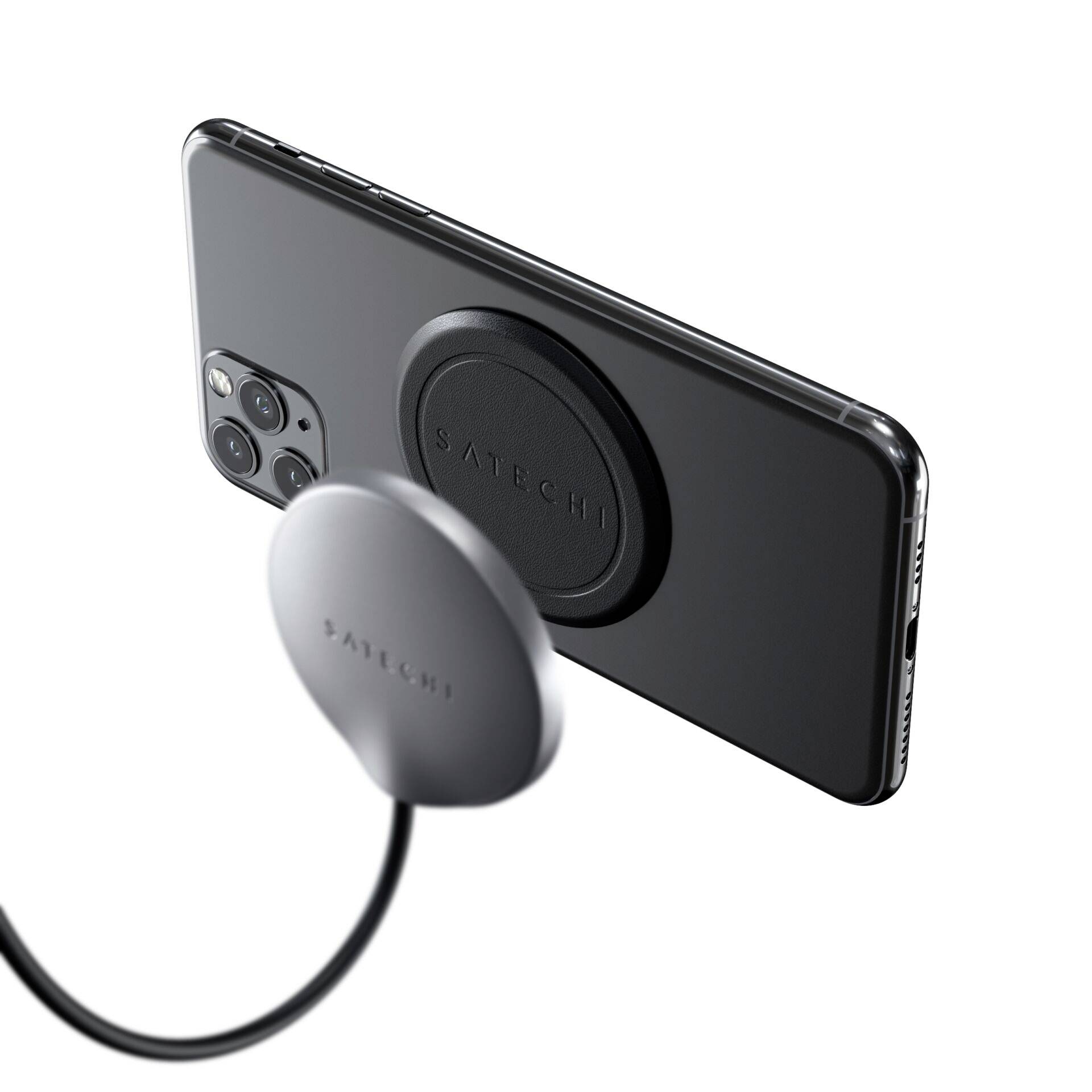 Ein Smartphone ist mit einem magnetischen Ladegerät befestigt, schwebend. Text auf dem Ladegerät: 'Satechi'. Hintergrund unscharf.