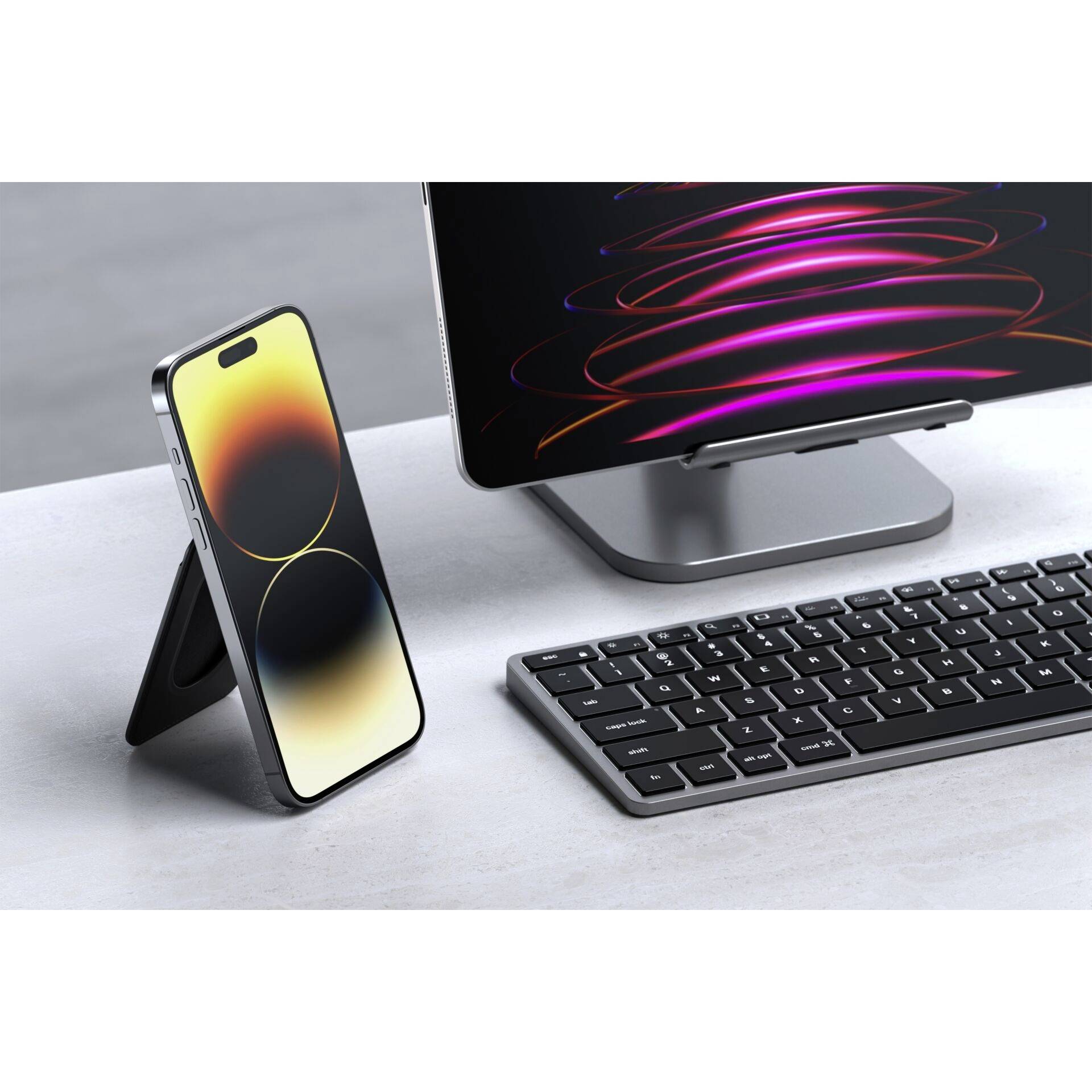 Ein Mobiltelefon steht aufrecht neben einer Tastatur und einem Monitor. Der Monitor zeigt bunte, abstrakte Linien auf schwarzem Hintergrund.