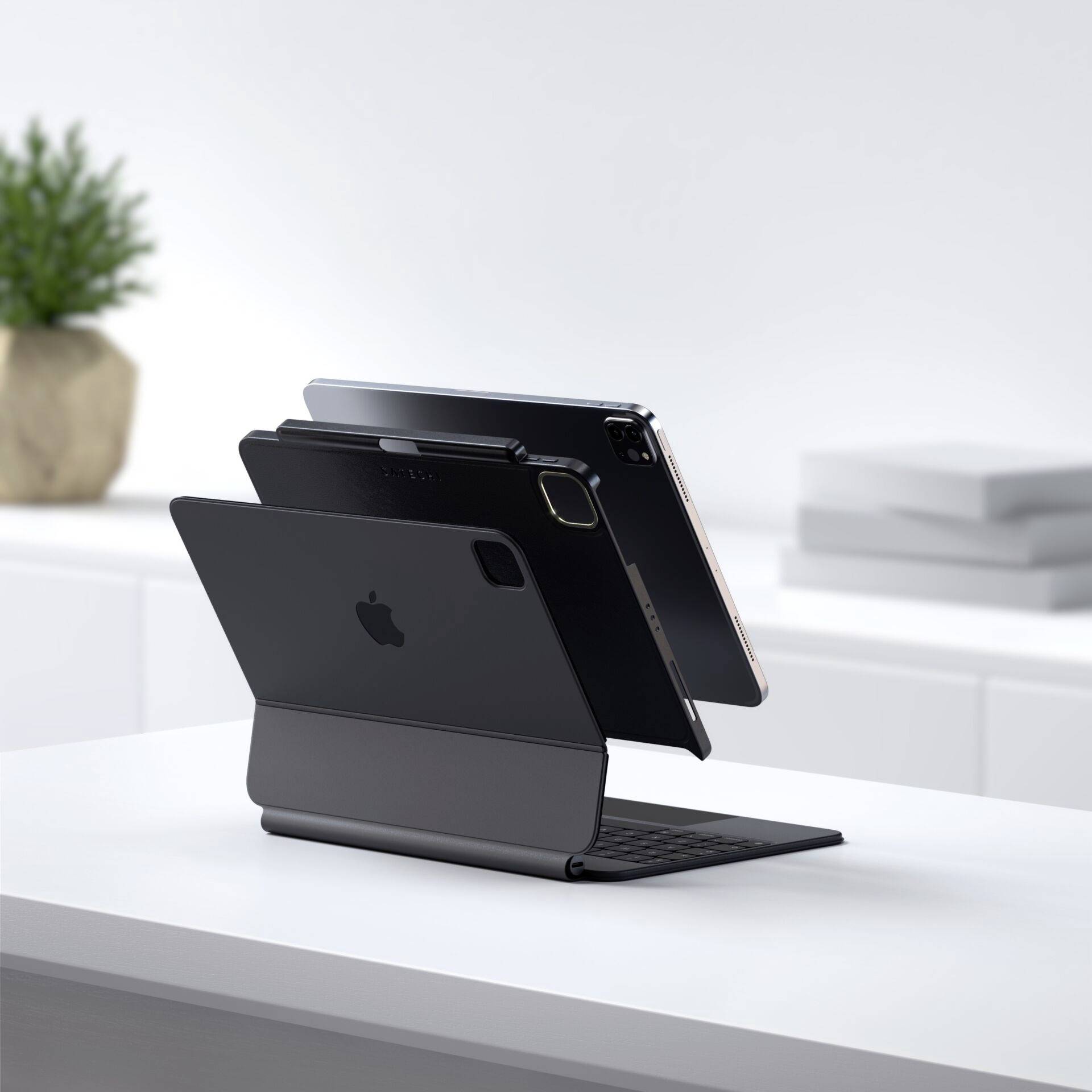 Ein Tablet mit Tastaturhülle steht auf einem Tisch. Im Hintergrund sind ein Pflanztopf und unscharfe Bürogeräte sichtbar.