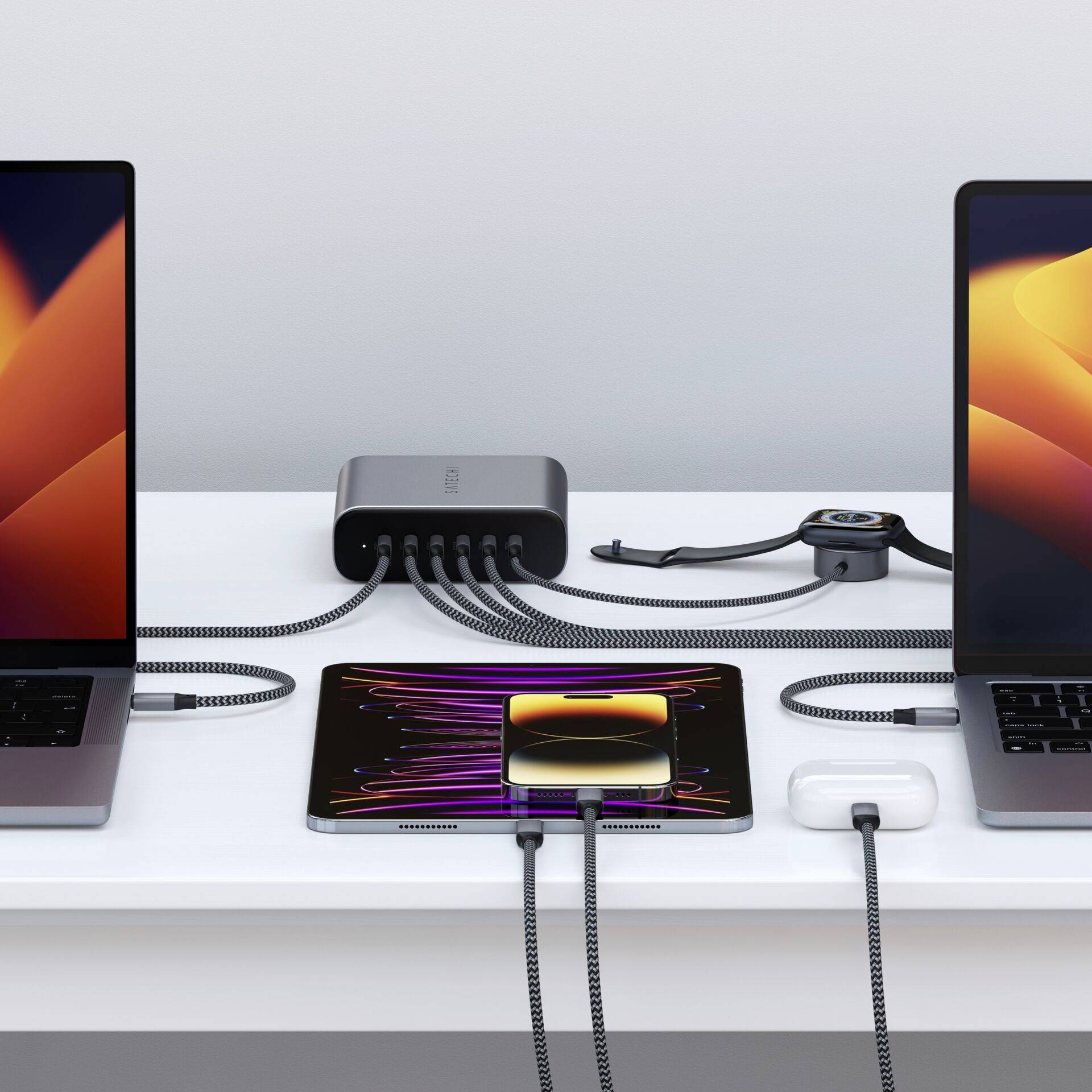 Fünf elektronische Geräte werden über ein Ladegerät mit mehreren Anschlüssen auf einem Tisch aufgeladen.