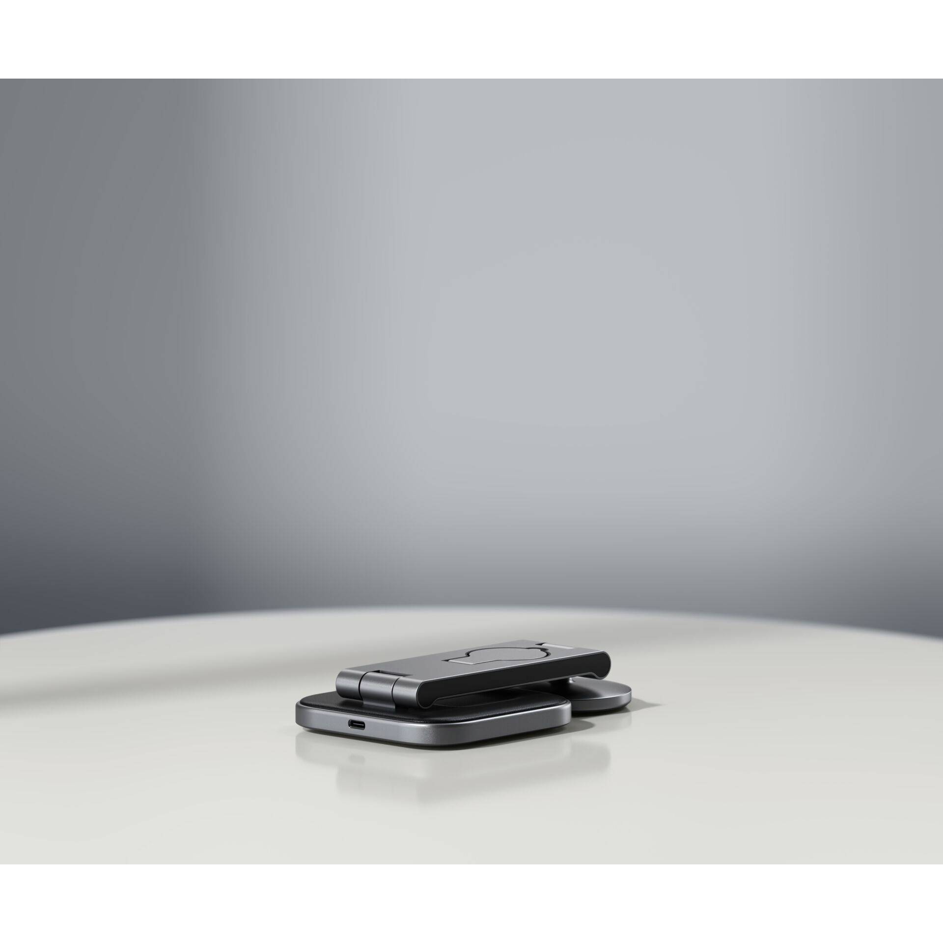 Ein zusammengeklapptes, modernes Klapphandy liegt auf einem Tisch mit einem minimalistischen, grauen Hintergrund.