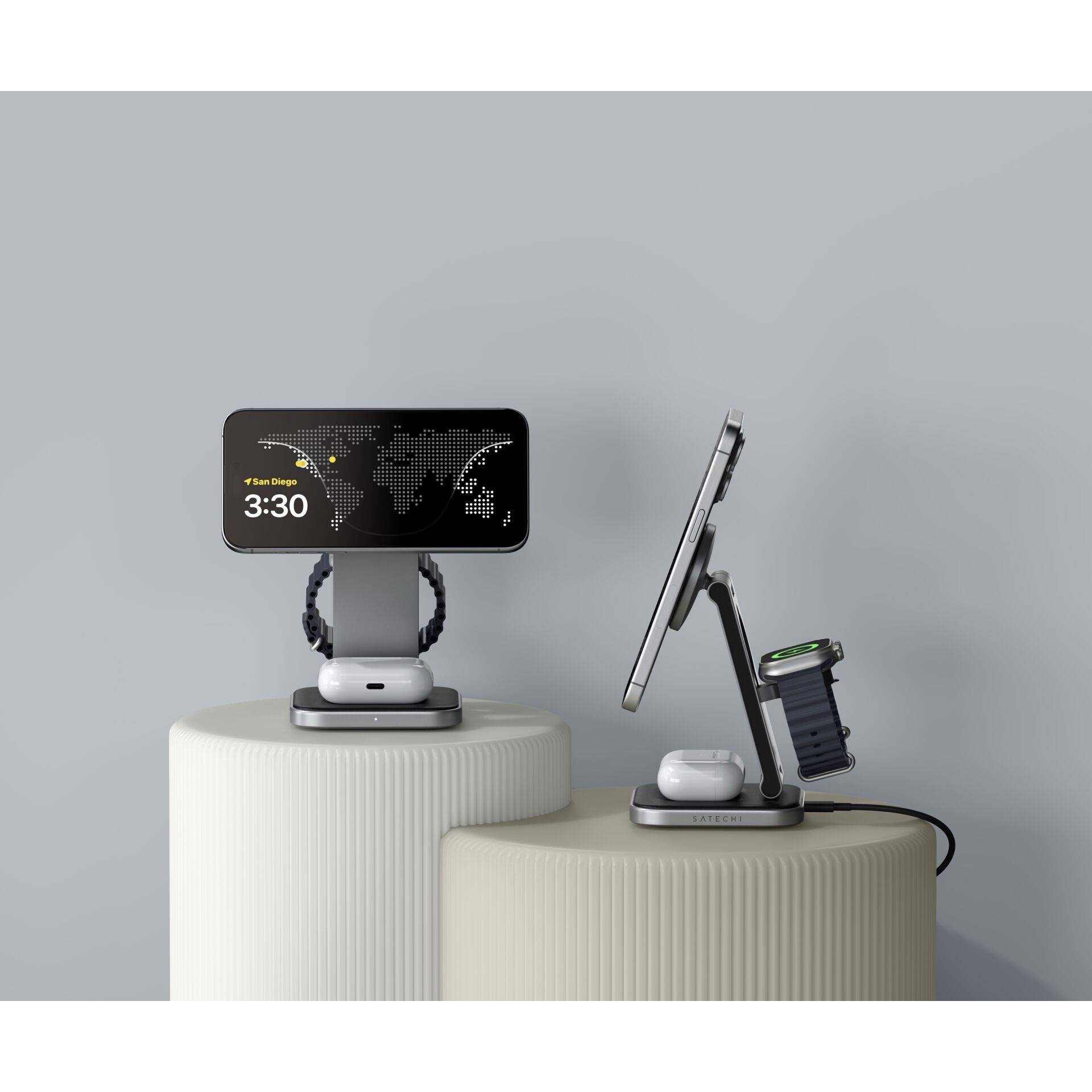 Smartphone und Uhr auf Ladestationen, beide zeigen die Uhrzeit '3:30'. Kabel verbindet die Station mit einer Energiequelle.