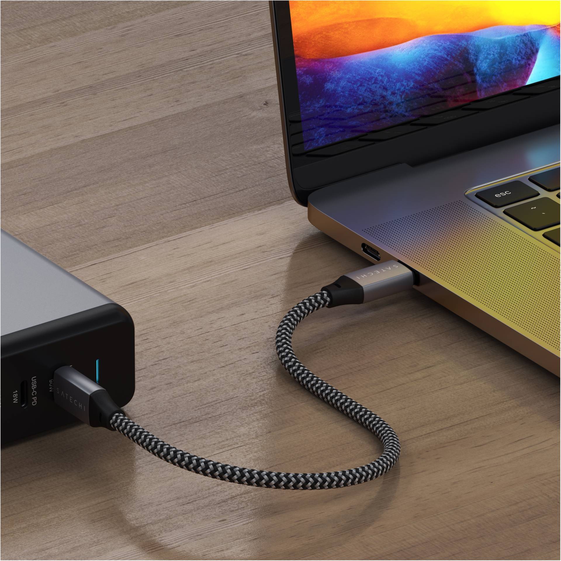 Ein Laptop ist über ein geflochtenes USB-C-Kabel mit einer externen Festplatte verbunden.