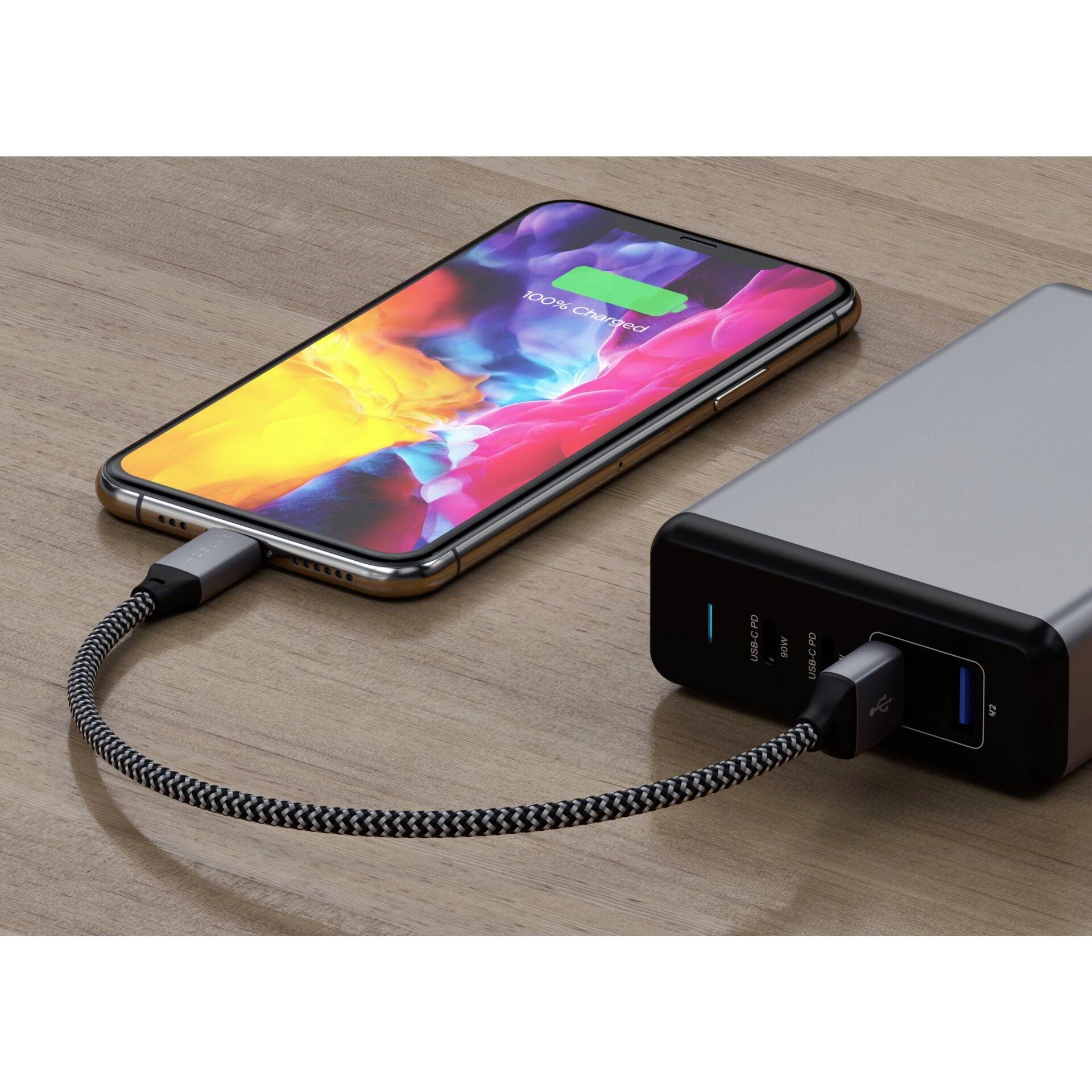 Ein Smartphone wird mit einem Ladekabel an eine Powerbank angeschlossen und zeigt den Ladezustand mit einem grünen Batteriesymbol an.