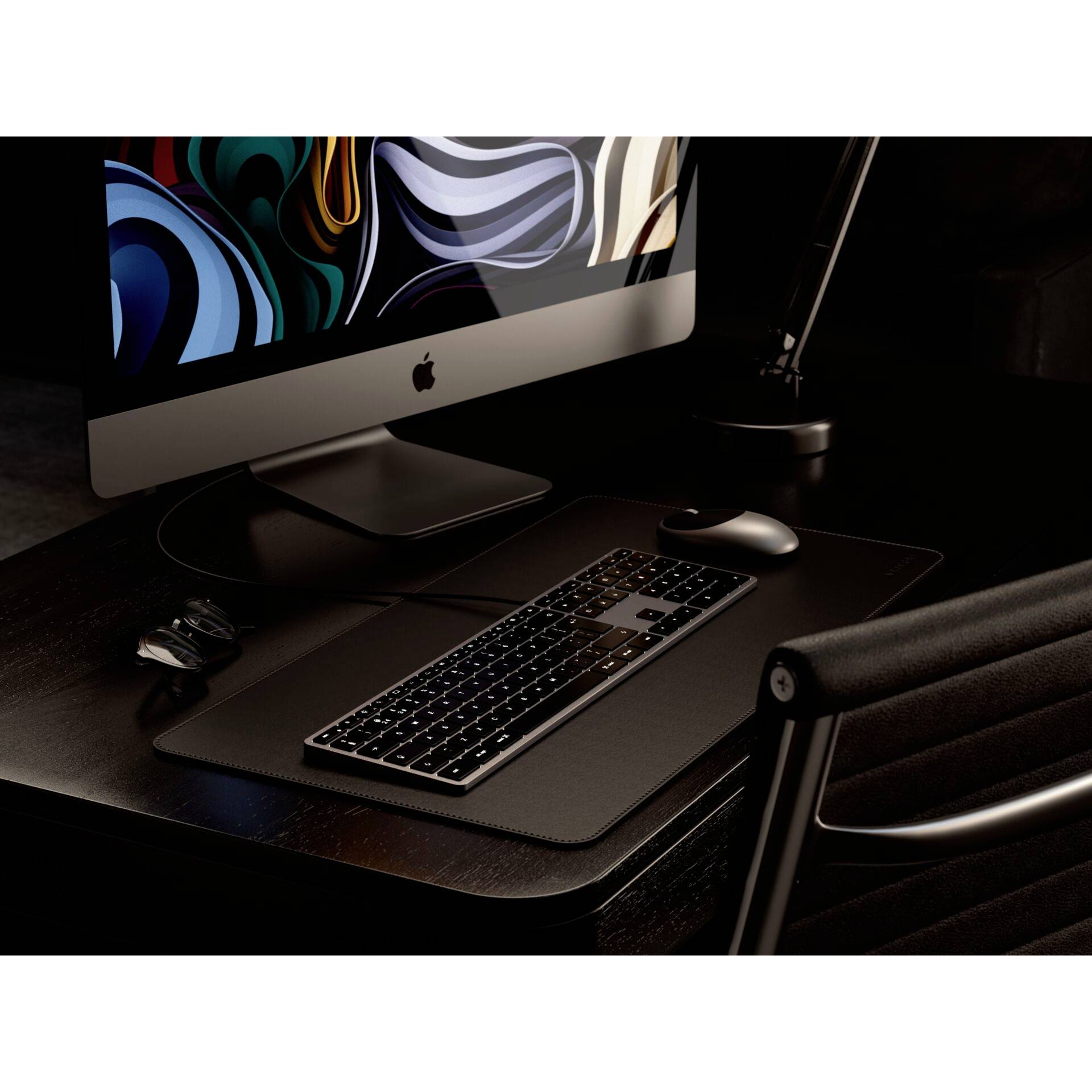 Ein moderner Schreibtisch mit einem Computer und einer beleuchteten Tastatur auf einer dunklen Oberfläche, stimmungsvolles Licht.