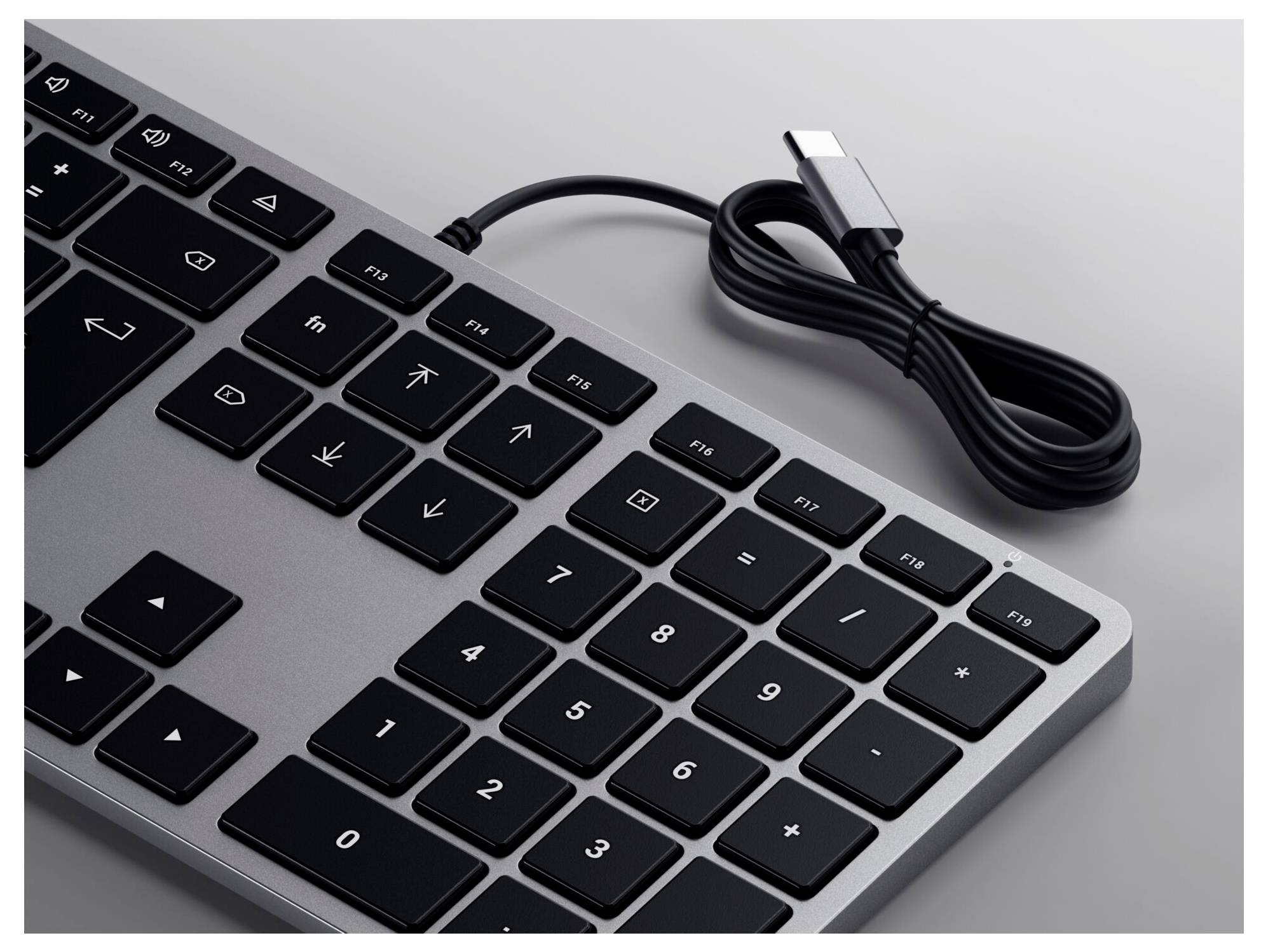 Tastatur in Schwarz mit numerischem Tastenfeld, angeschlossen über ein USB-Kabel. Layout umfasst Funktionstasten und Ziffernblock.