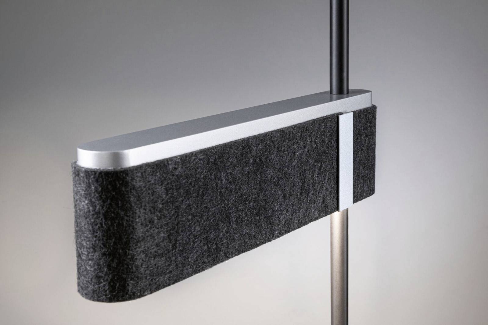 Ein modernes, schlankes Heizkörperdesign mit rechteckiger, dunkler Oberfläche und heller Metallkante, das an einem Rohr befestigt ist.