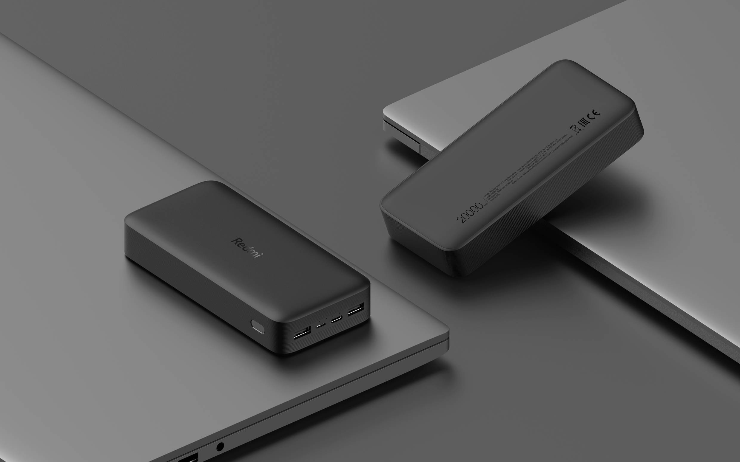 Zwei Powerbanks auf Laptops, eine mit der Aufschrift 10000mAh. Beide haben USB-Anschlüsse an der Vorderseite. Minimalistisches Design.