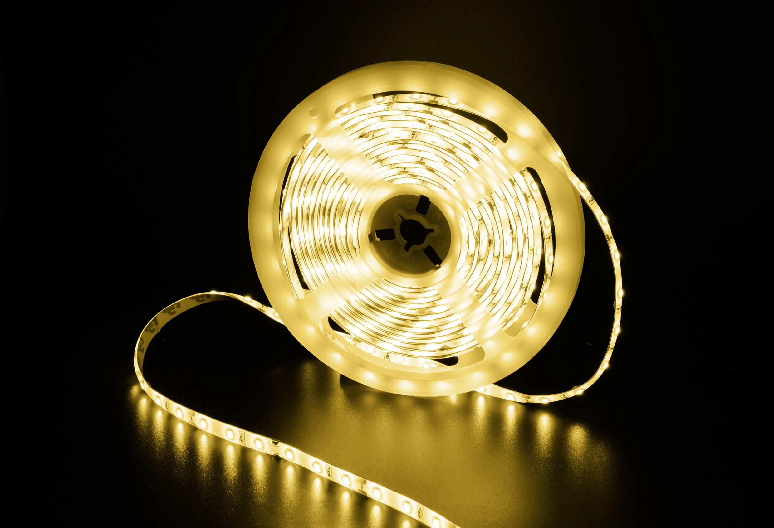 Eine aufgewickelte LED-Lichterkette leuchtet warmweiß auf einem dunklen Hintergrund.