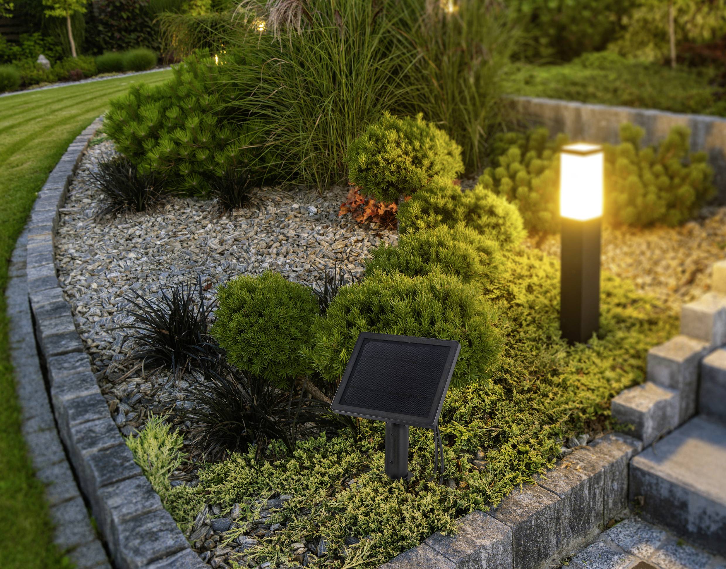 Ein landschaftlich gestalteter Garten mit einer Solaranlage neben einer leuchtenden Außenleuchte, umgeben von Sträuchern und Steinstufen, die zu einer Terrasse führen.