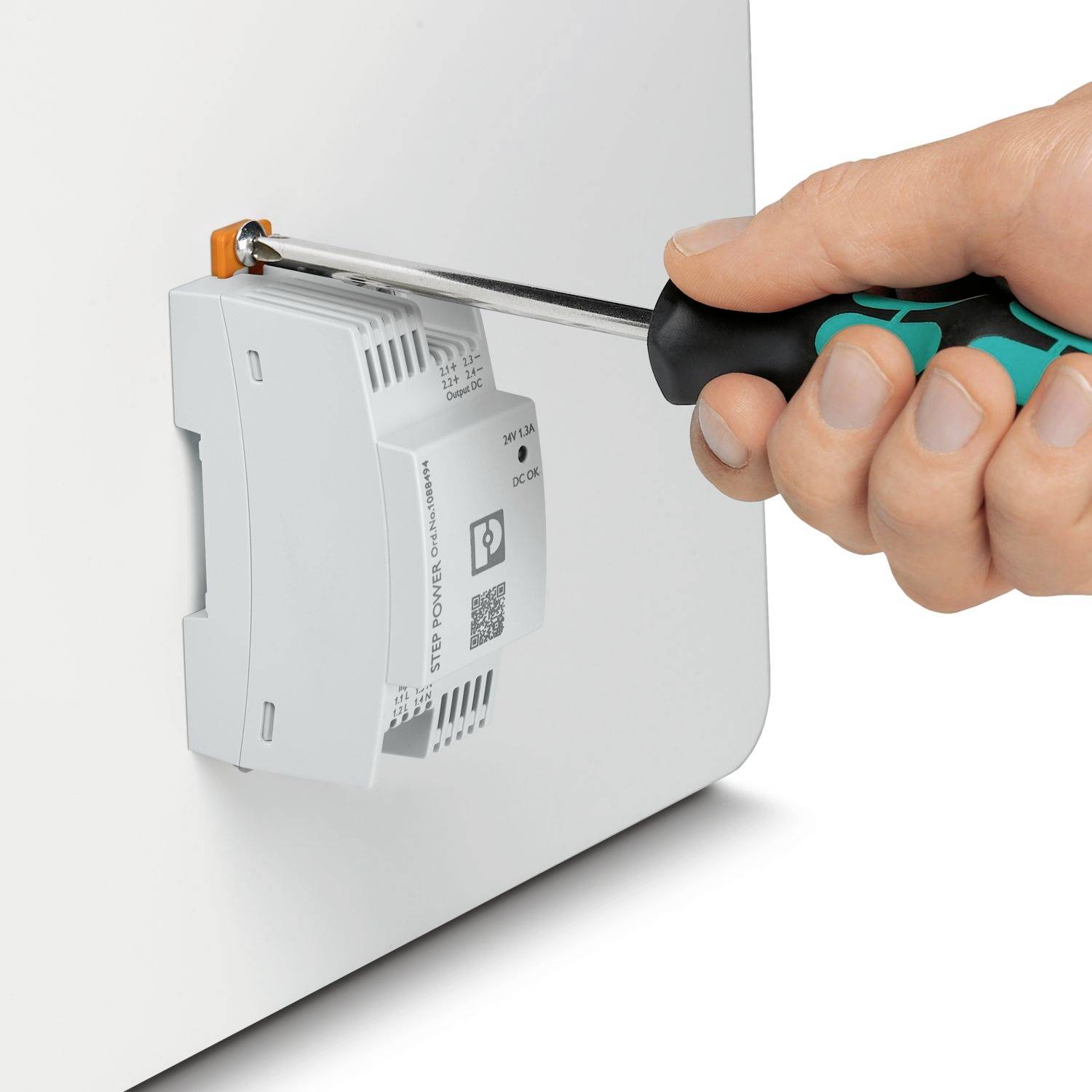 Hand zieht eine Schraube mit einem Schraubenzieher an einem elektrischen Gerät im Gehäuse fest.