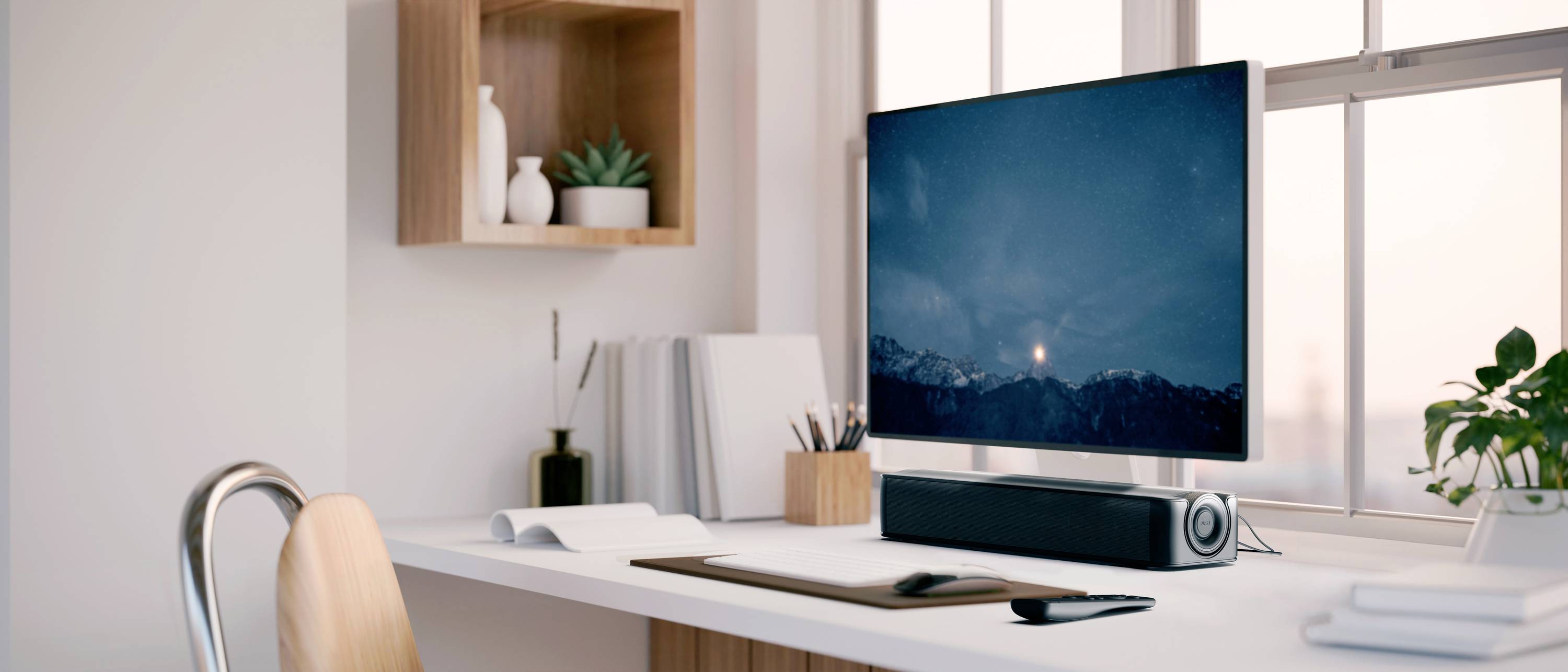 Moderner Schreibtisch mit Computerbildschirm, Tastatur, Lautsprecher und Pflanzen; ruhige, gut beleuchtete Arbeitsumgebung.