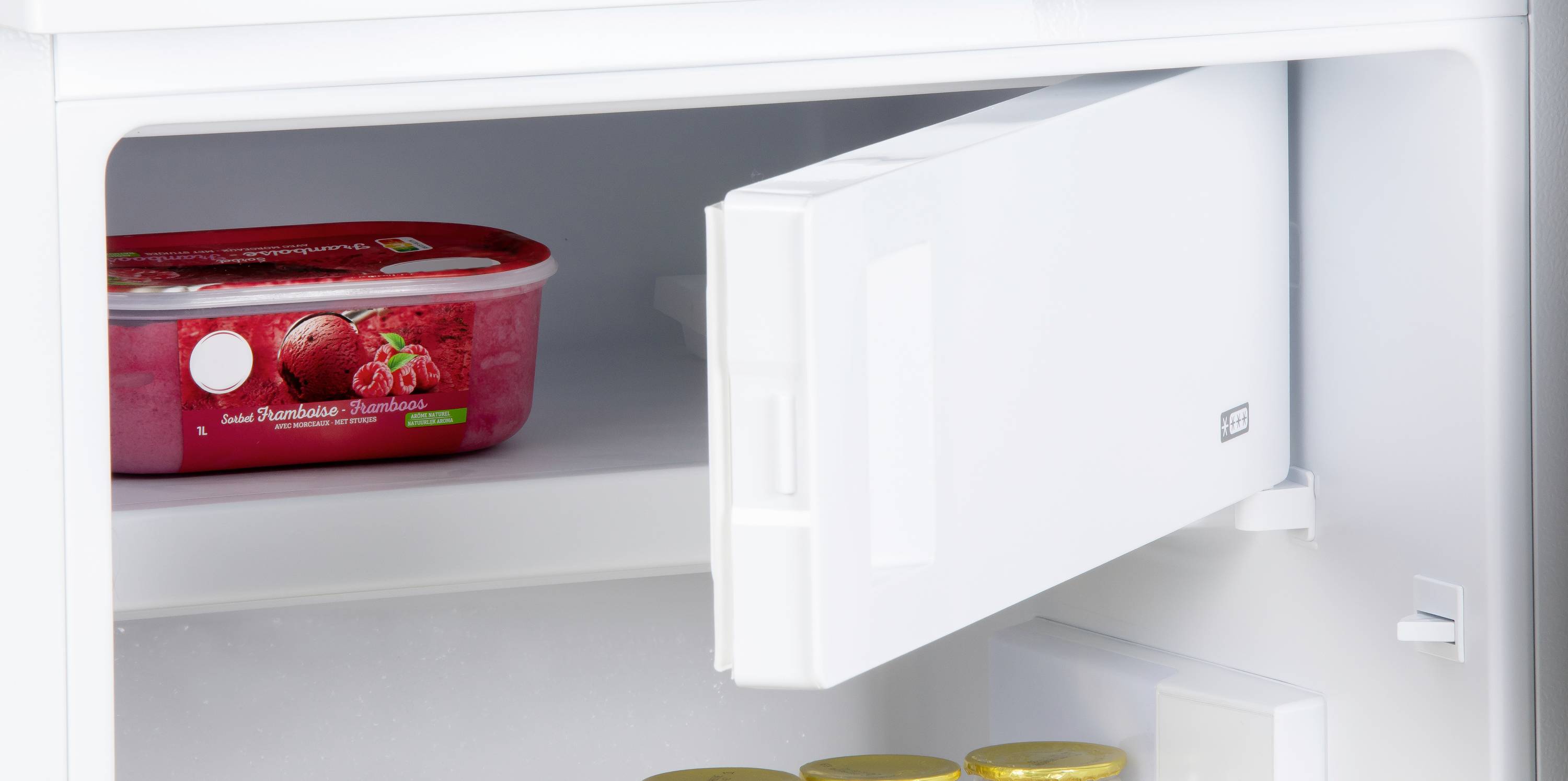 Ein offener Gefrierschrank mit einer Packung Eis und mehreren gelben Dosen im Inneren.