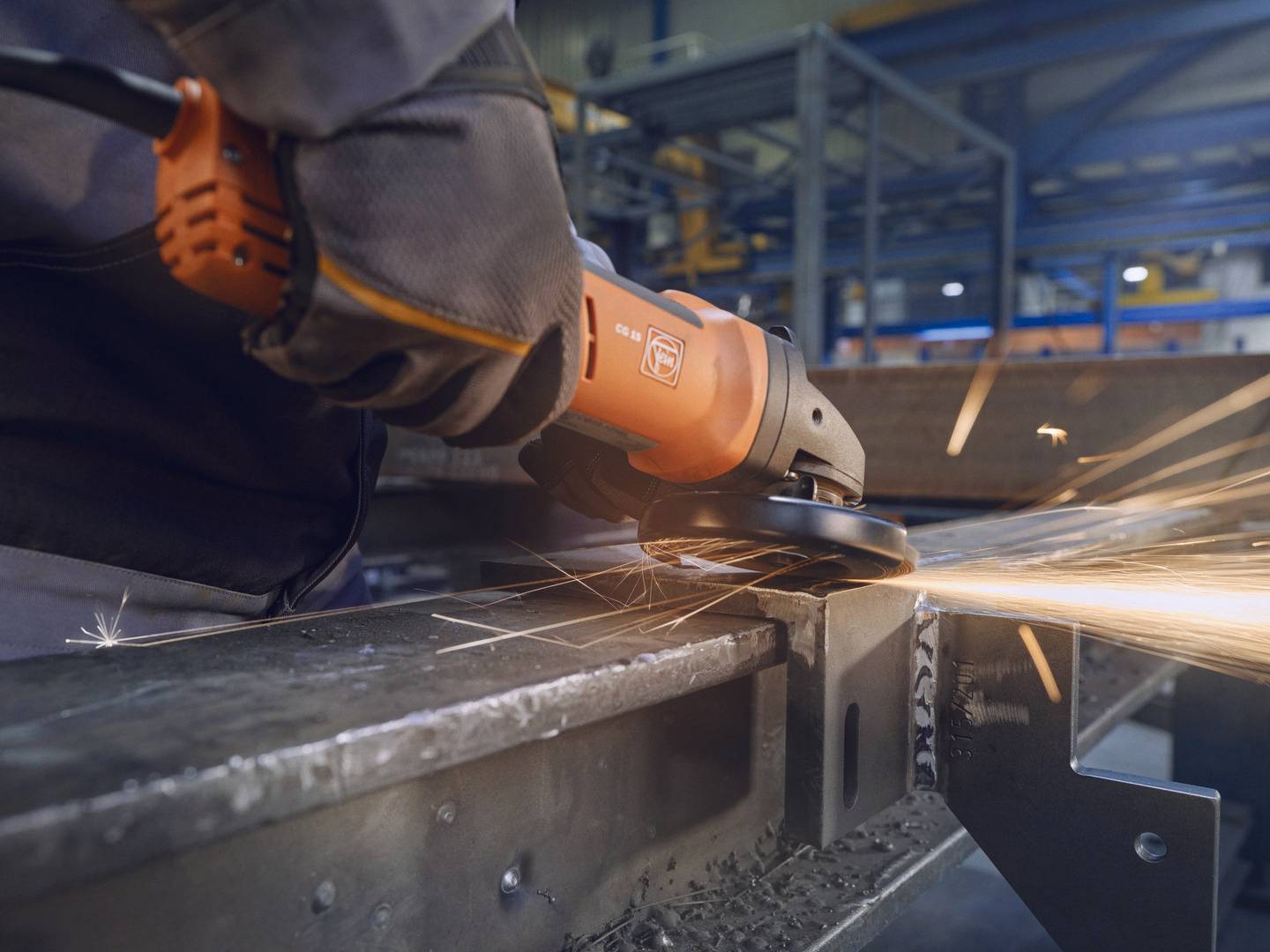 Eine Person schleift mit einer Schleifmaschine Metall, Funken fliegen. Arbeitsplatz in einer industriellen Umgebung.