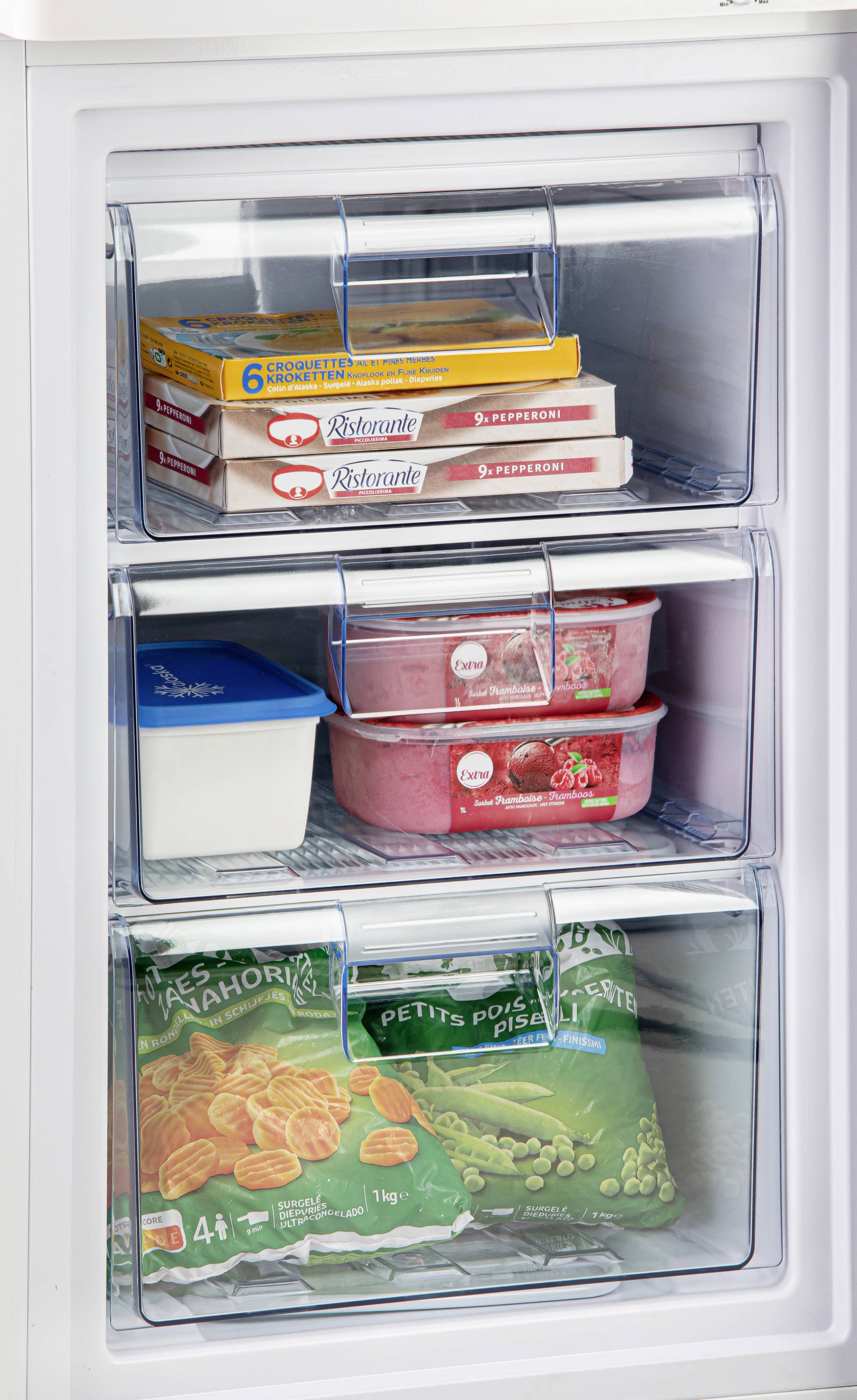 Ein Gefrierschrank mit drei Fächern, gefüllt mit verpackter Tiefkühlpizza, Eiscreme und gefrorenem Gemüse wie Erbsen und Möhren.