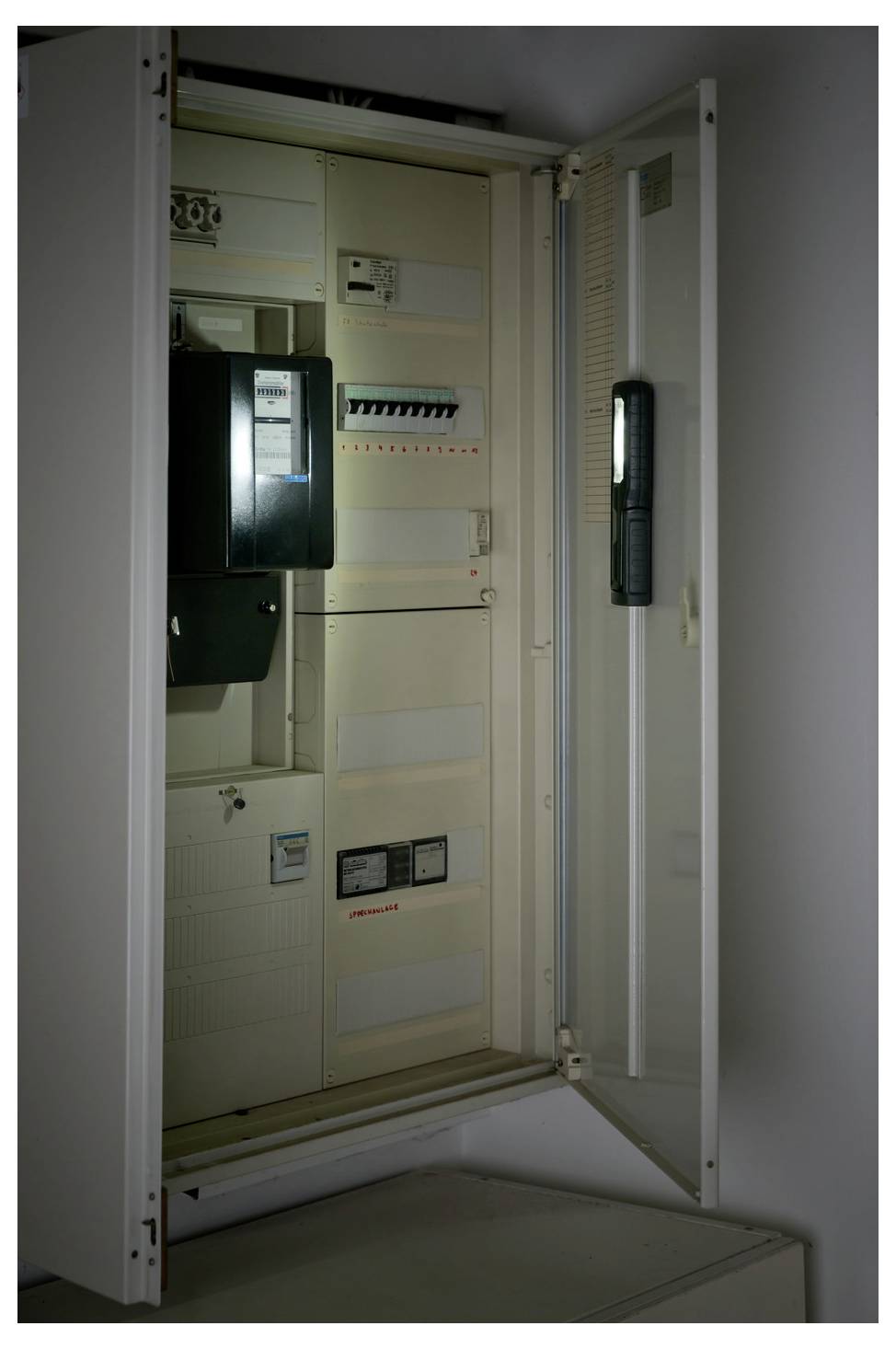 Offener Elektroverteilerschrank mit freiliegenden Schutzschaltern, Messgeräten und Verkabelung in einem wandmontierten Schaltfeld.