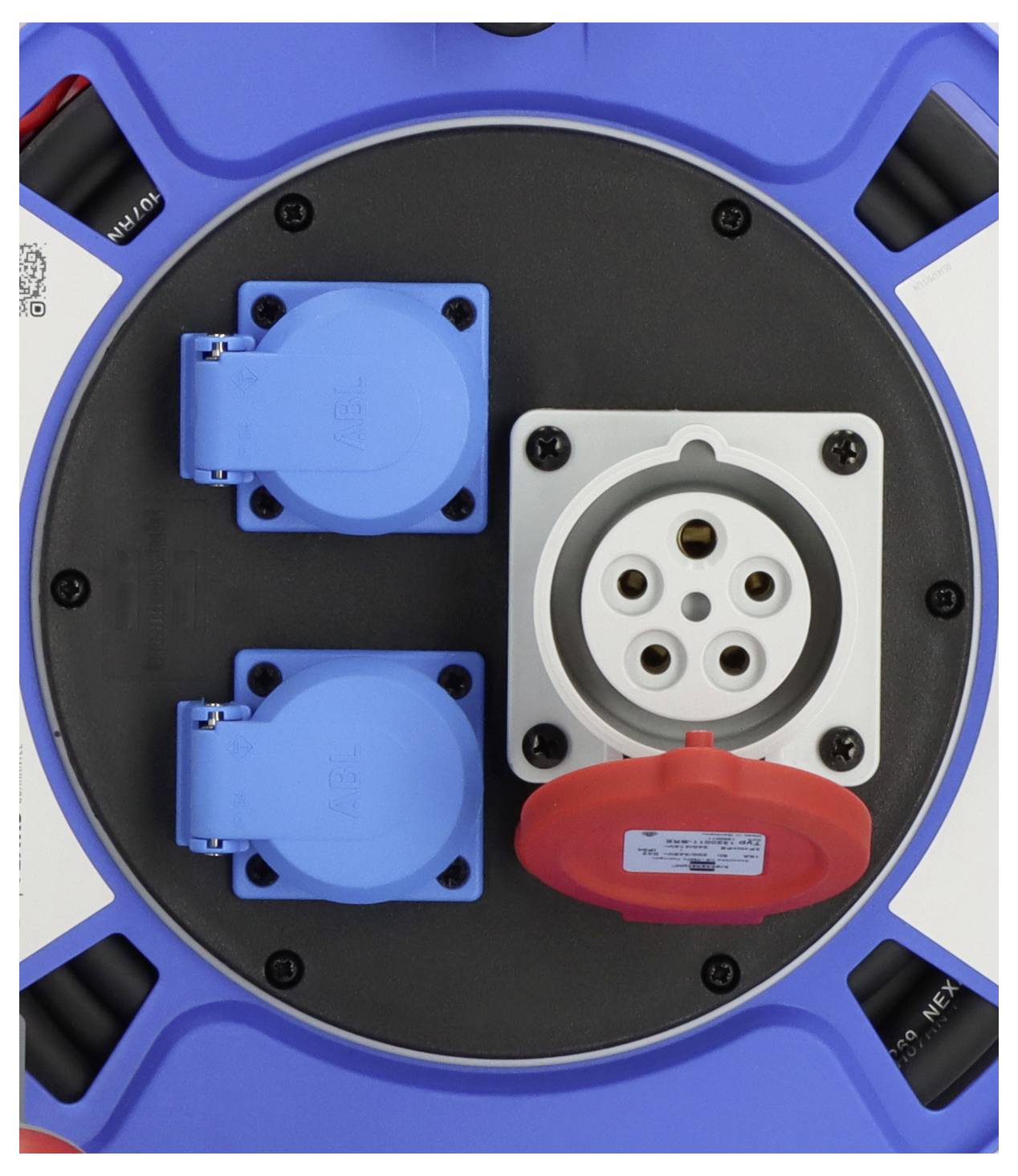 Nahaufnahme einer Ladebuchse eines Elektrofahrzeugs mit zwei blauen Wechselstromsockeln und einem abgedeckten weißen Gleichstromstecker mit einer roten Kappe.