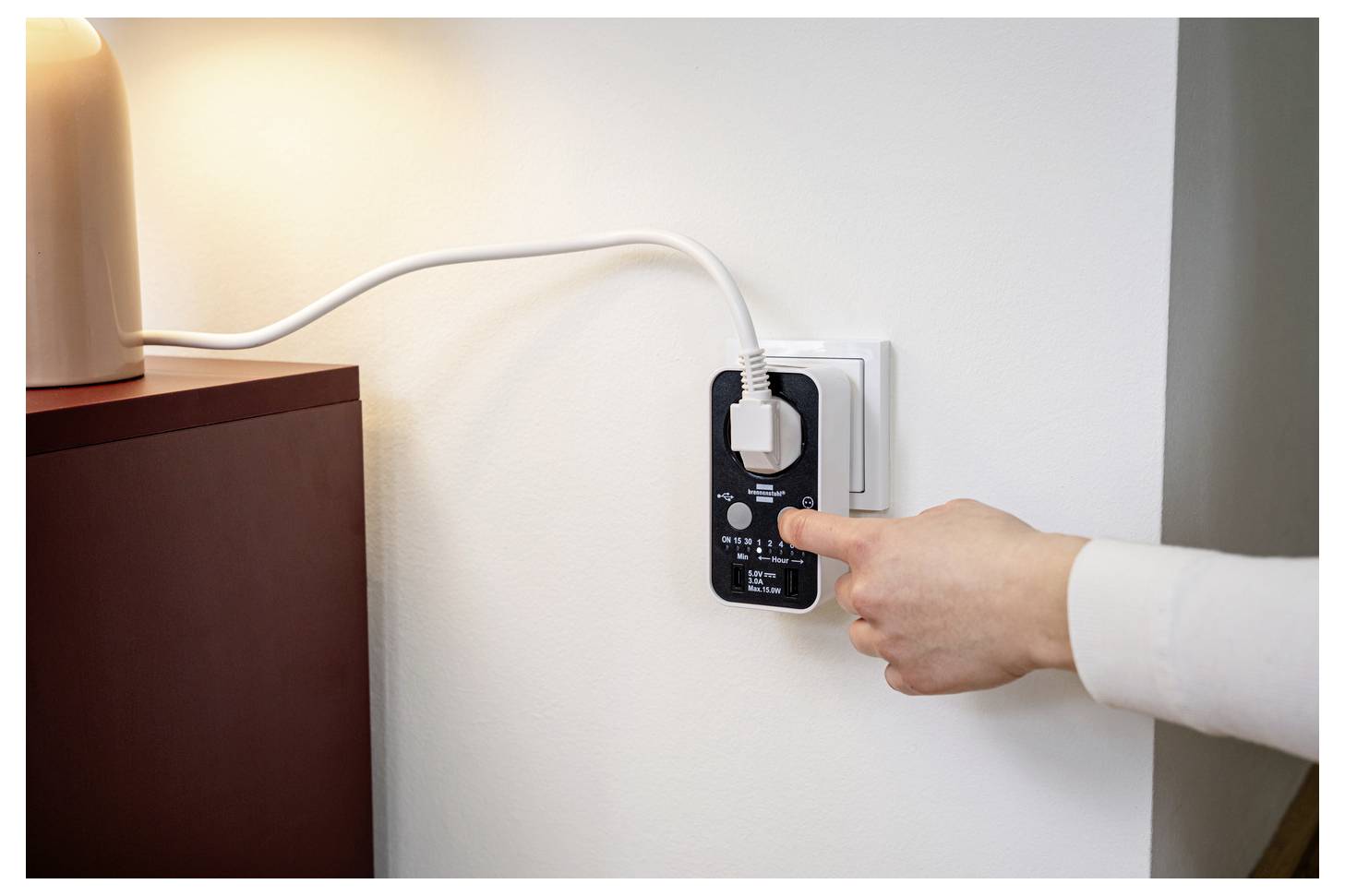 # Bild einer Hand, die eine Lampe mit einem Inline-Strommessgerät oder intelligenten Stecker in eine Wandsteckdose steckt und die Kontrolle des Stromverbrauchs zeigt.