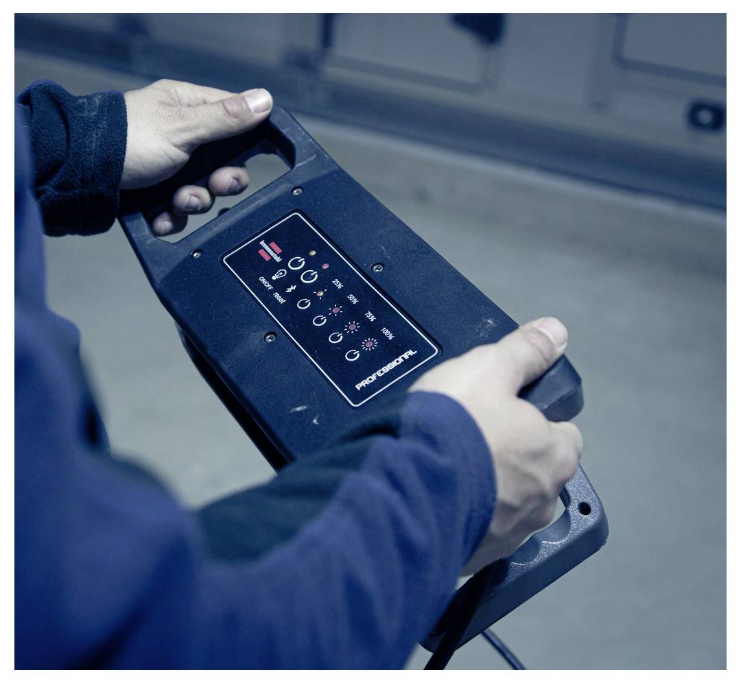 Person holding a black power tool or battery pack with a control panel and icons, shown close-up indoors.Person mit schwarzem Elektrowerkzeug oder Akku mit Bedienfeld und Symbolen, nahaufnahme in Innenräumen gezeigt.