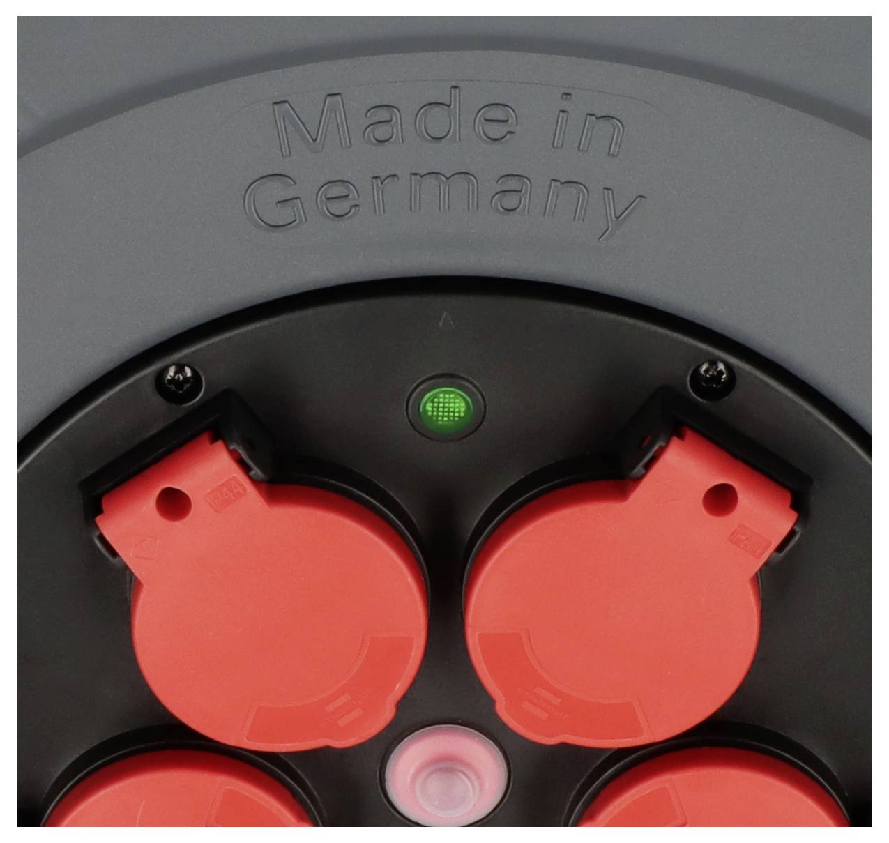 Graue Steckdosenleiste mit vier roten Steckplätzen und grünem Licht darüber. Aufschrift oben 'Made in Germany'.