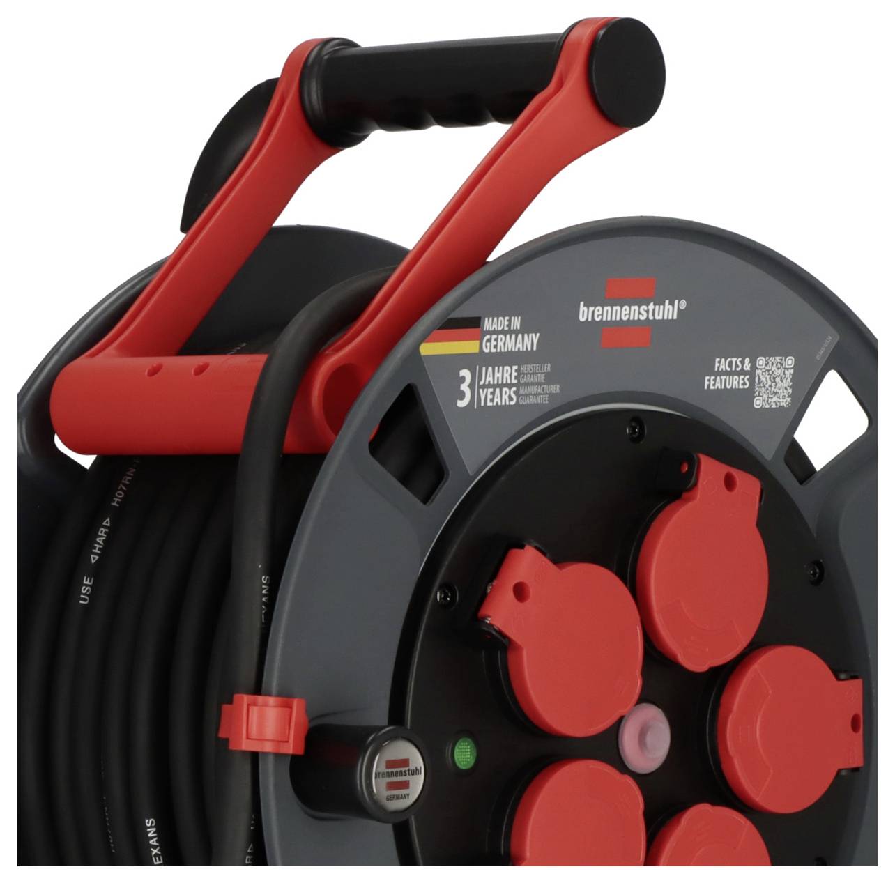 Ein Kabeltrommel mit rotem Griff und Steckdosen. Etikett zeigt 'Made in Germany' und '3 Jahre Garantie'.