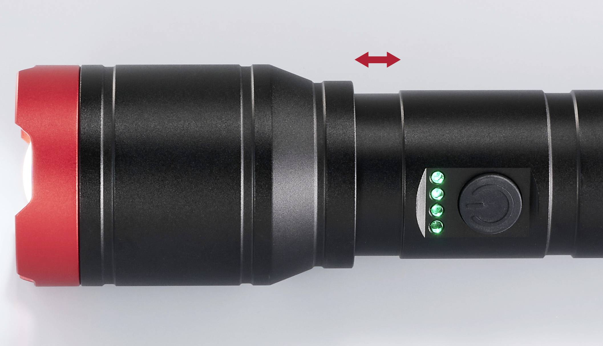 Schwarze Taschenlampe mit rotem Rand, drei leuchtenden grünen LED-Anzeigen und einem Ein-/Ausschalter. Pfeil zeigt die ausziehbare Funktion.