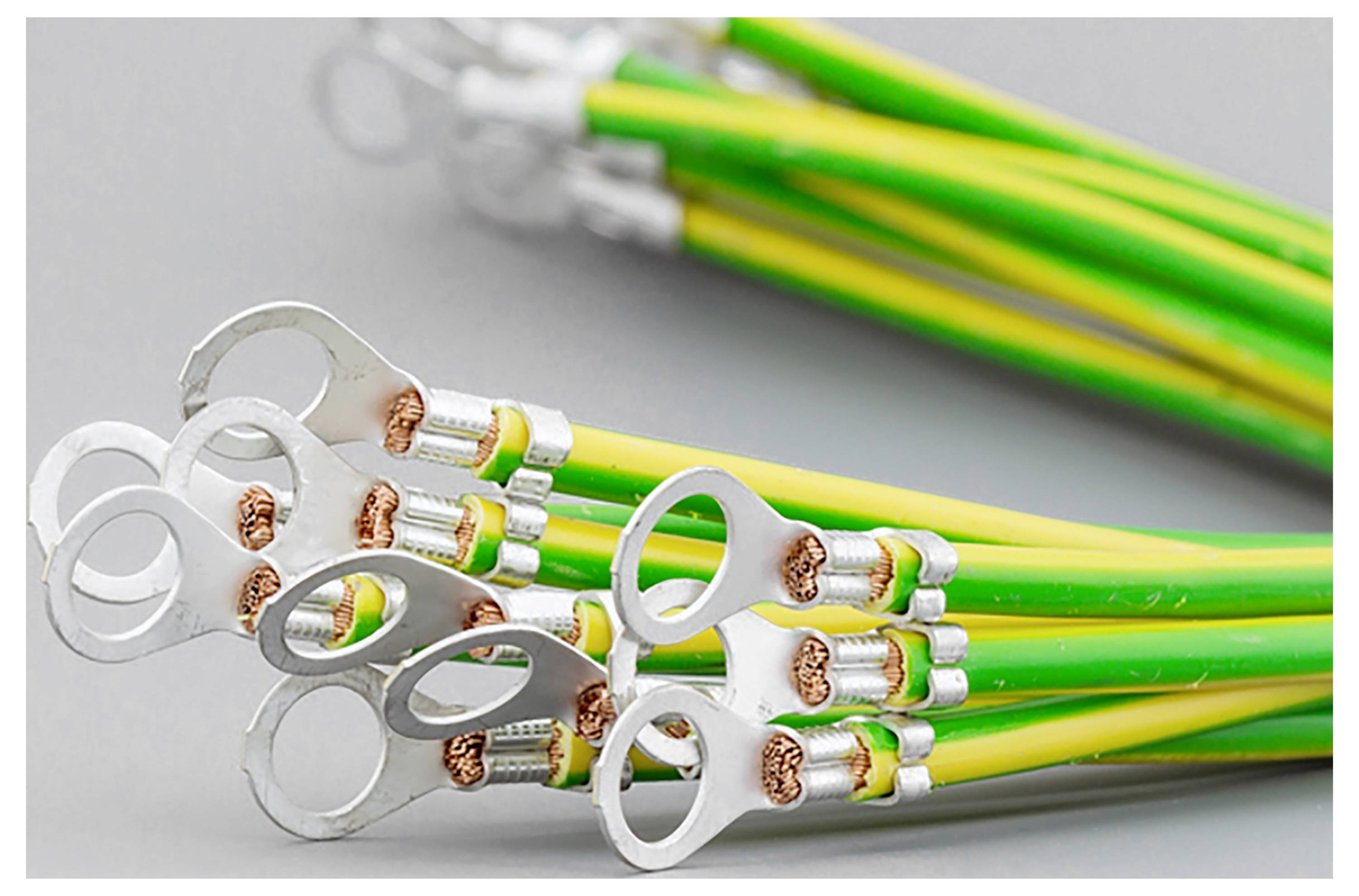 Ein Bündel von gelb-grünen elektrischen Kabeln mit metallischen Ringklemmen an den Enden liegt auf einer grauen Oberfläche.