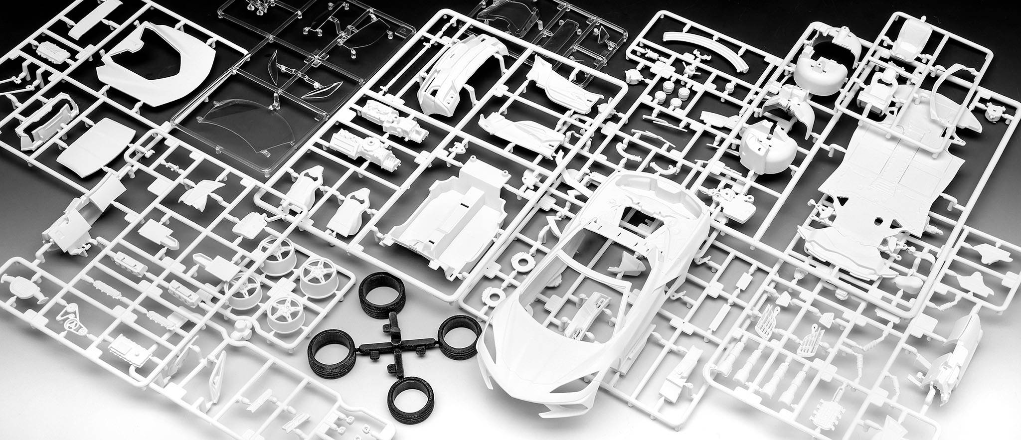 Bausatz für ein Modellauto, bestehend aus mehreren Gussrahmen mit Autoteilen aus Kunststoff, teilweise zusammengebaut.