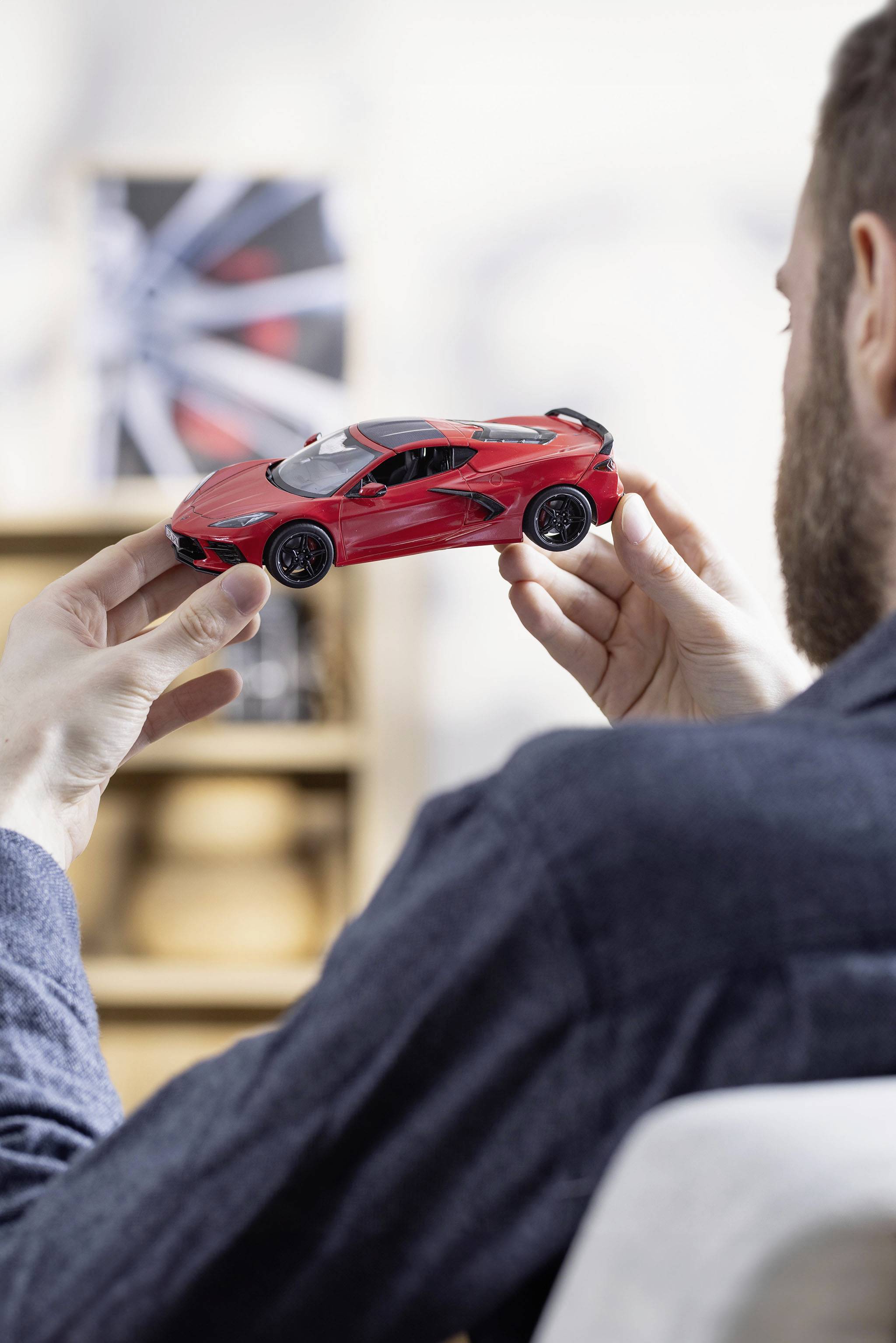 Eine Person hält ein Modellauto in Rot. Das Auto ist detailliert, und die Umgebung ist unscharf, was den Fokus auf das Auto setzt.