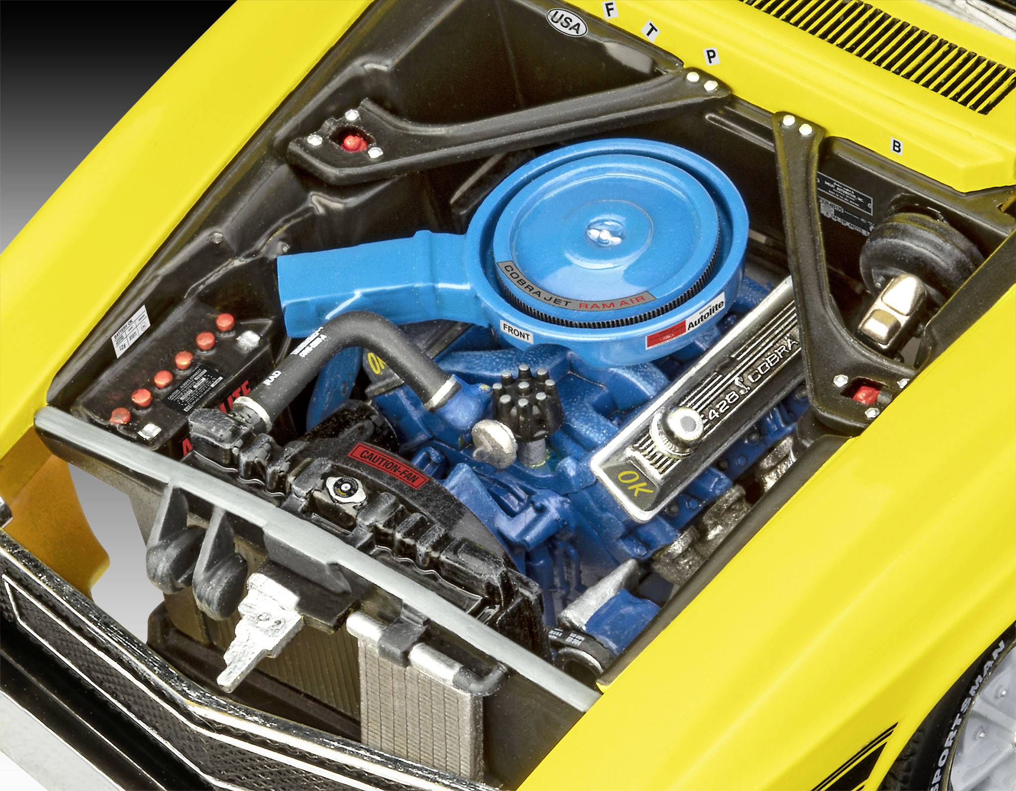 Der gelbe Sportwagen zeigt seinen Motorraum, in dem ein blauer V8-Motor mit schwarzen Schläuchen und Kabeln zentral platziert ist.