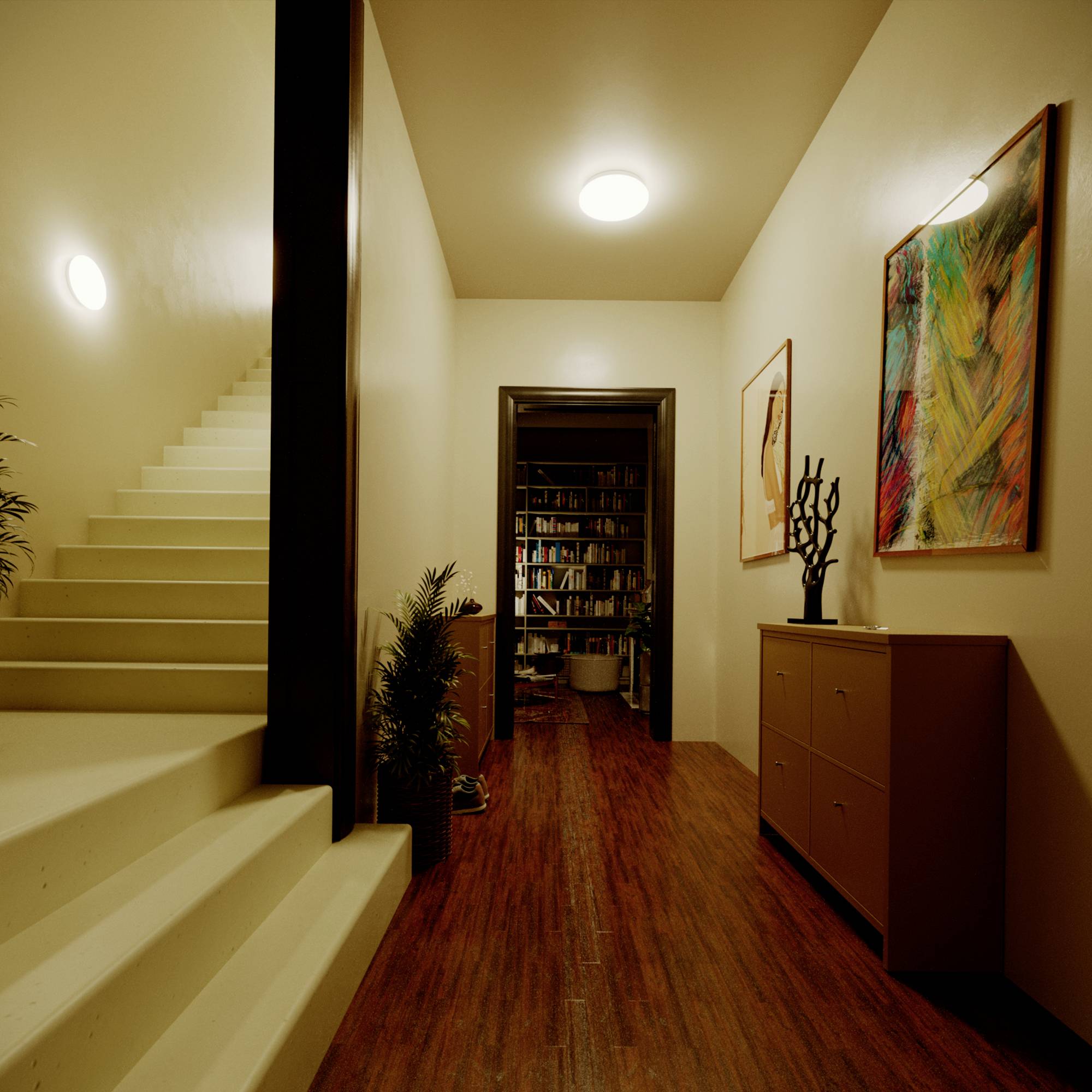 Ein Flur mit Holzfußboden, links eine Treppe. Rechts zwei Kunstwerke an der Wand, vorne führt der Flur in einen Raum mit Bücherregalen.