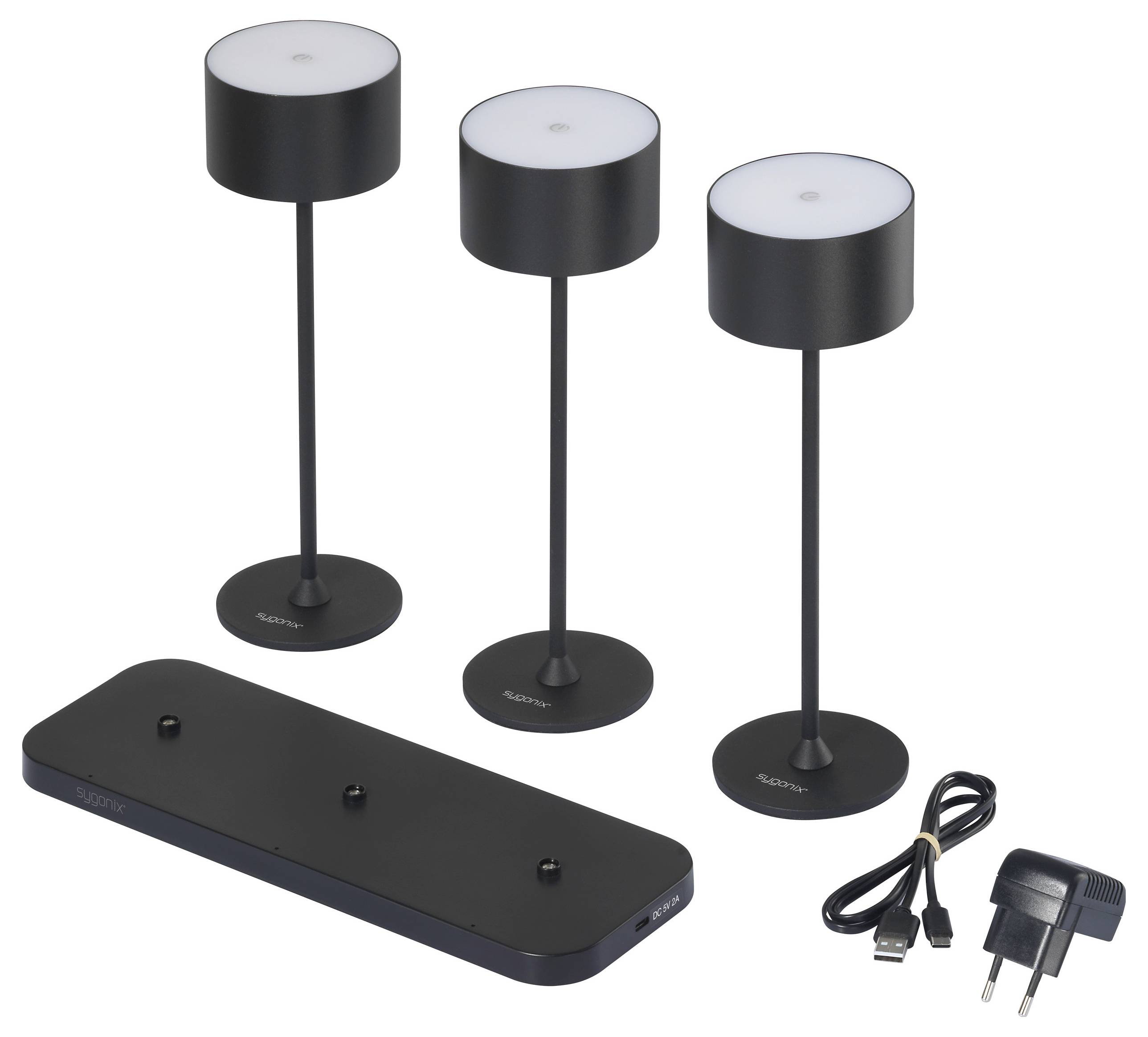 Drei schwarze, tragbare Tischlampen auf einer Ladestation. Rechts neben den Lampen liegt ein Netzteil mit USB-Kabel.