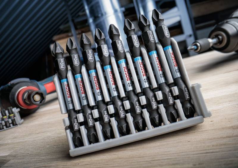 Satz Bohrer-Bits in einem Halter auf einem Tisch in einer Werkstatt. Im Hintergrund unscharfe Werkzeuge zu sehen.