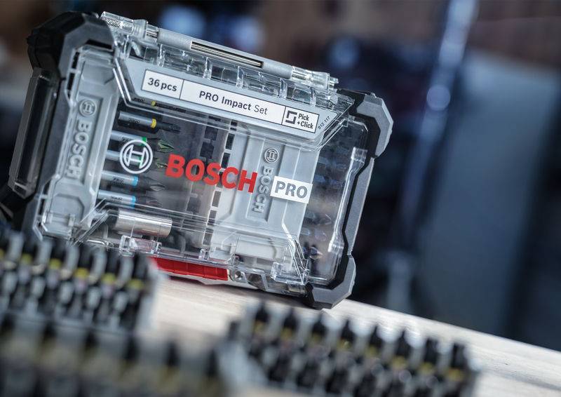 Abgebildet ist ein Bosch PRO Impact Set in einer transparenten Box mit 36 Teilen, auf einem unscharfen Hintergrund in einer Werkstatt.