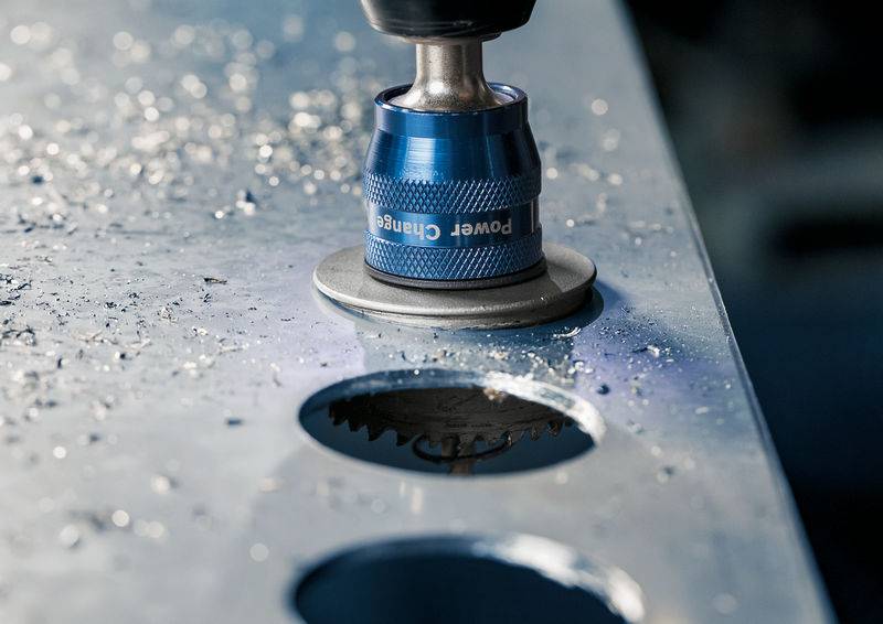 Nahaufnahme eines Metallbohrers, der präzise Löcher in eine Metallplatte bohrt. Umgebende Metallspäne zeigen die Aktivität des Bohrprozesses.