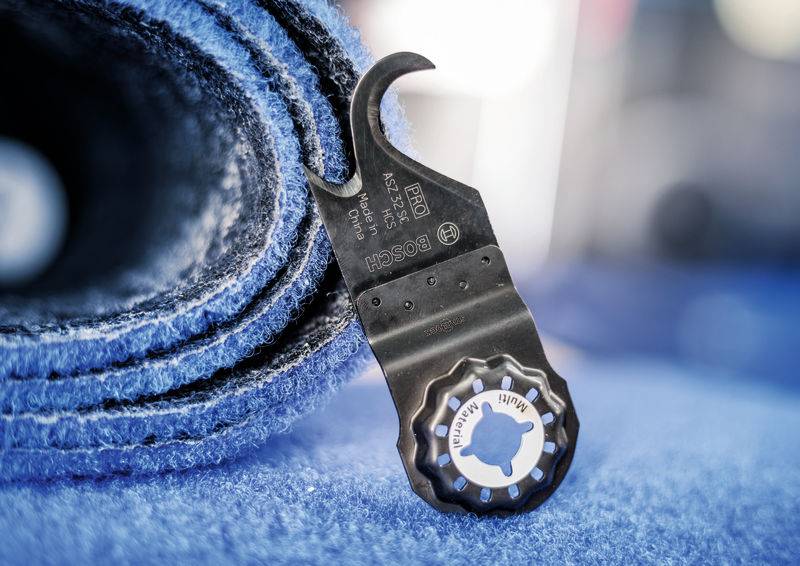 Eine schwarze Metallsägeklinge liegt auf einer zusammengerollten, blauen Schleifmatte.