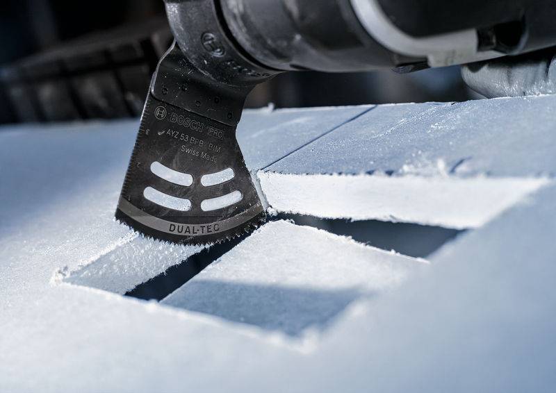 Eine oszillierende Säge schneidet präzise durch eine weiße Oberfläche, erzeugt klare, rechteckige Ausschnitte.