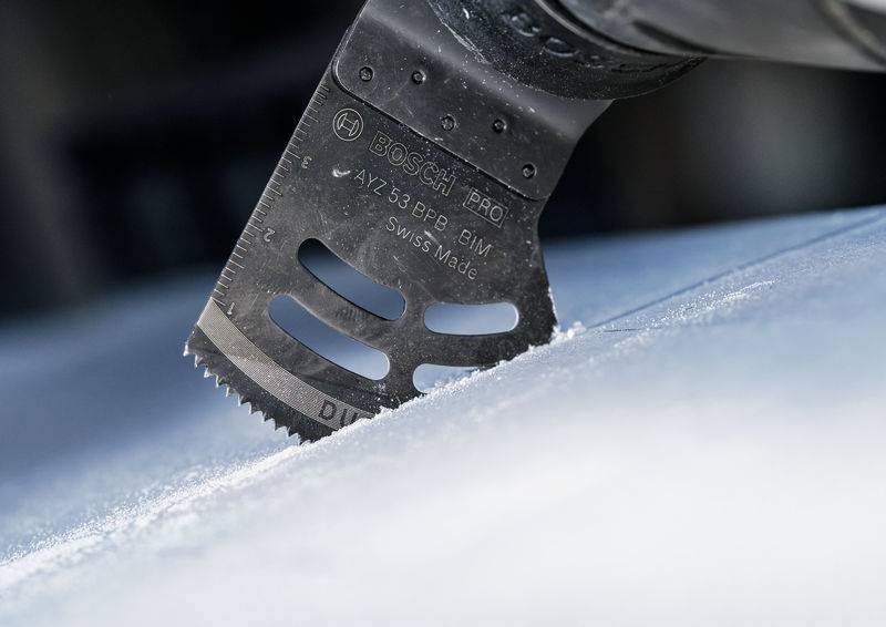 Nahaufnahme eines Multimaster-Sägeblatts, das in einem Winkel über eine Metalloberfläche geführt wird, um präzise Schnitte zu ermöglichen.