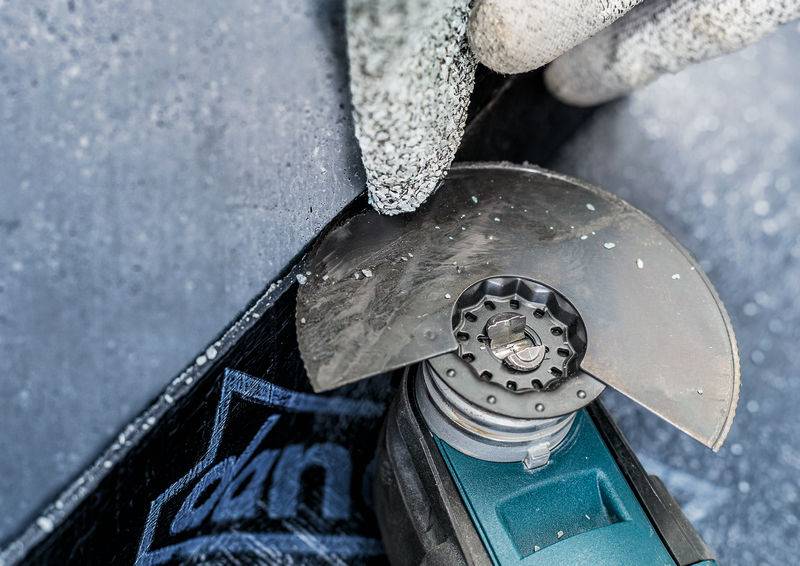 Eine Hand mit Schutzhandschuhen hält eine Trennscheibe, die Metall schneidet. Funken fliegen, es ist eine Arbeitssituation.